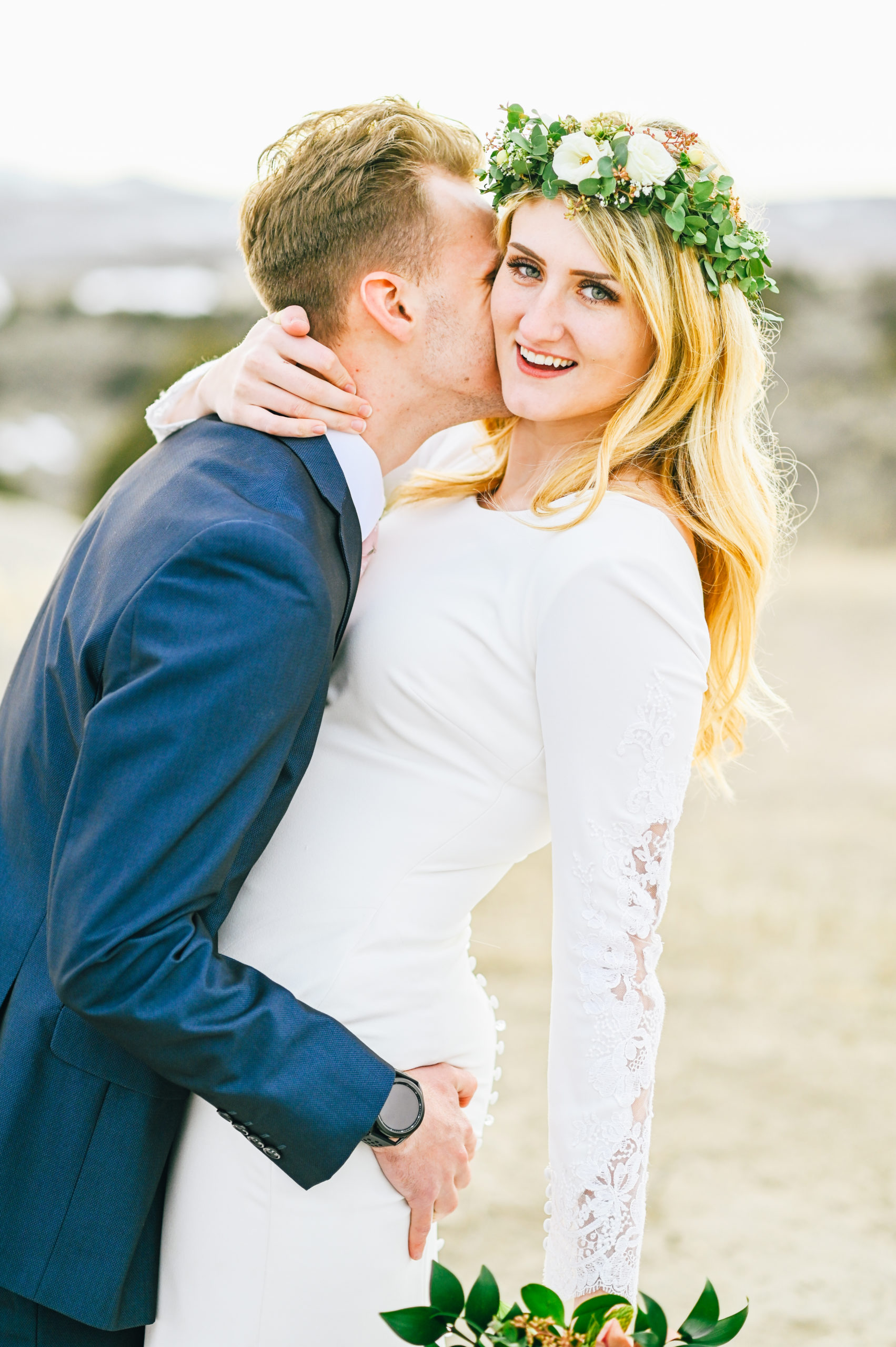 groom embracing bride and kissing her cheek 