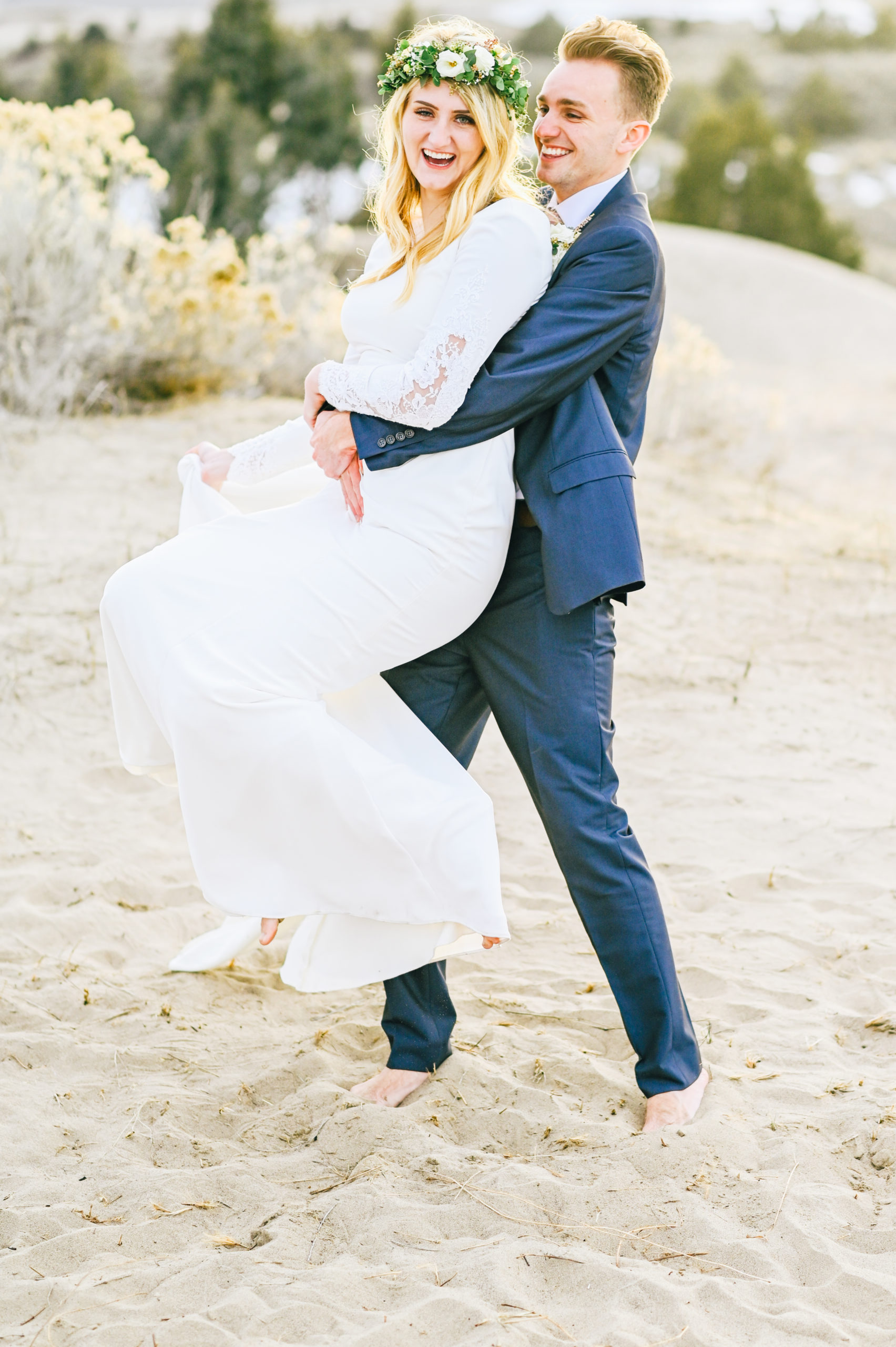 bride and groom laughing together while groom lifts her up