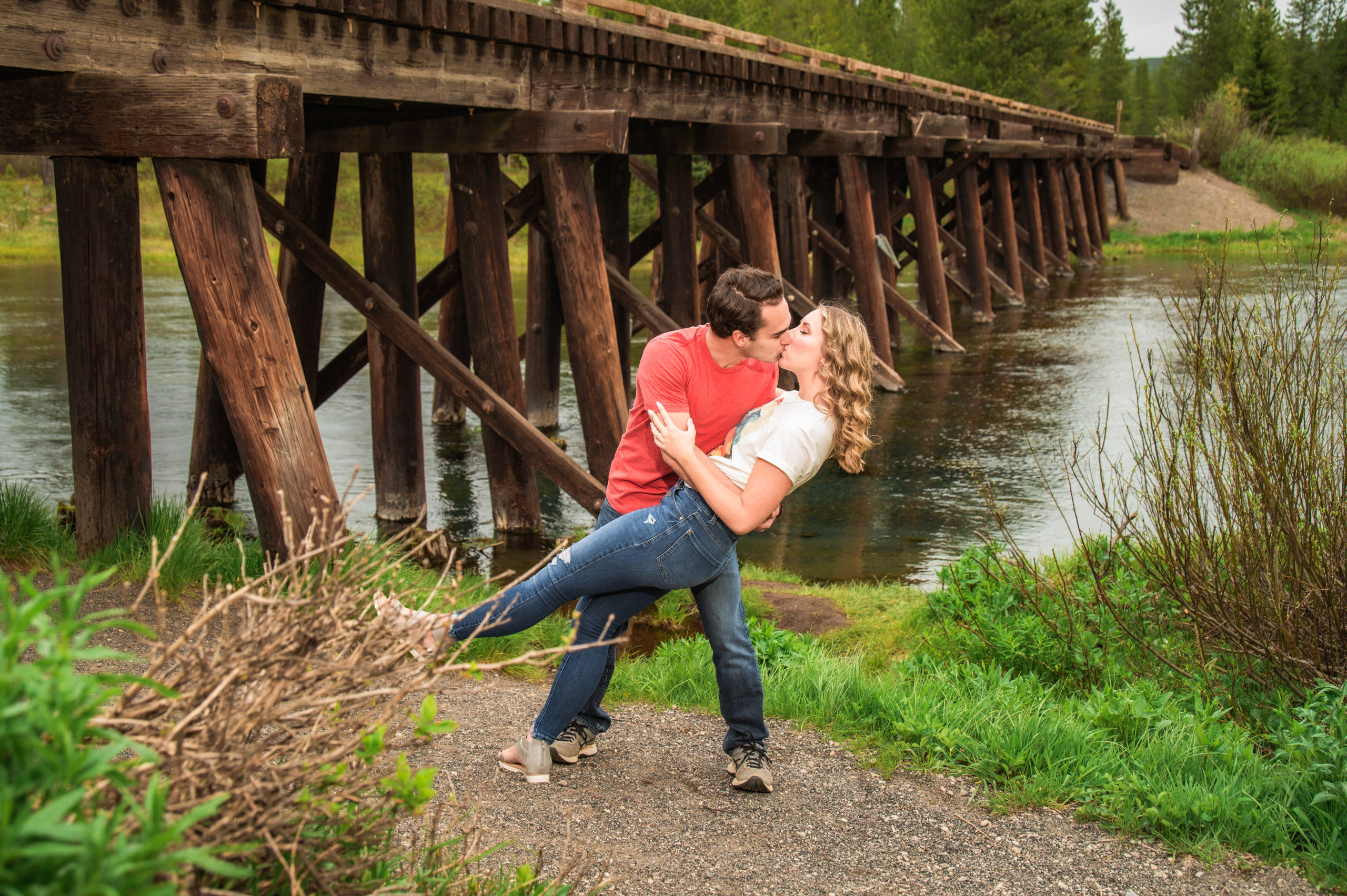 man holding and kissing woman near bridge