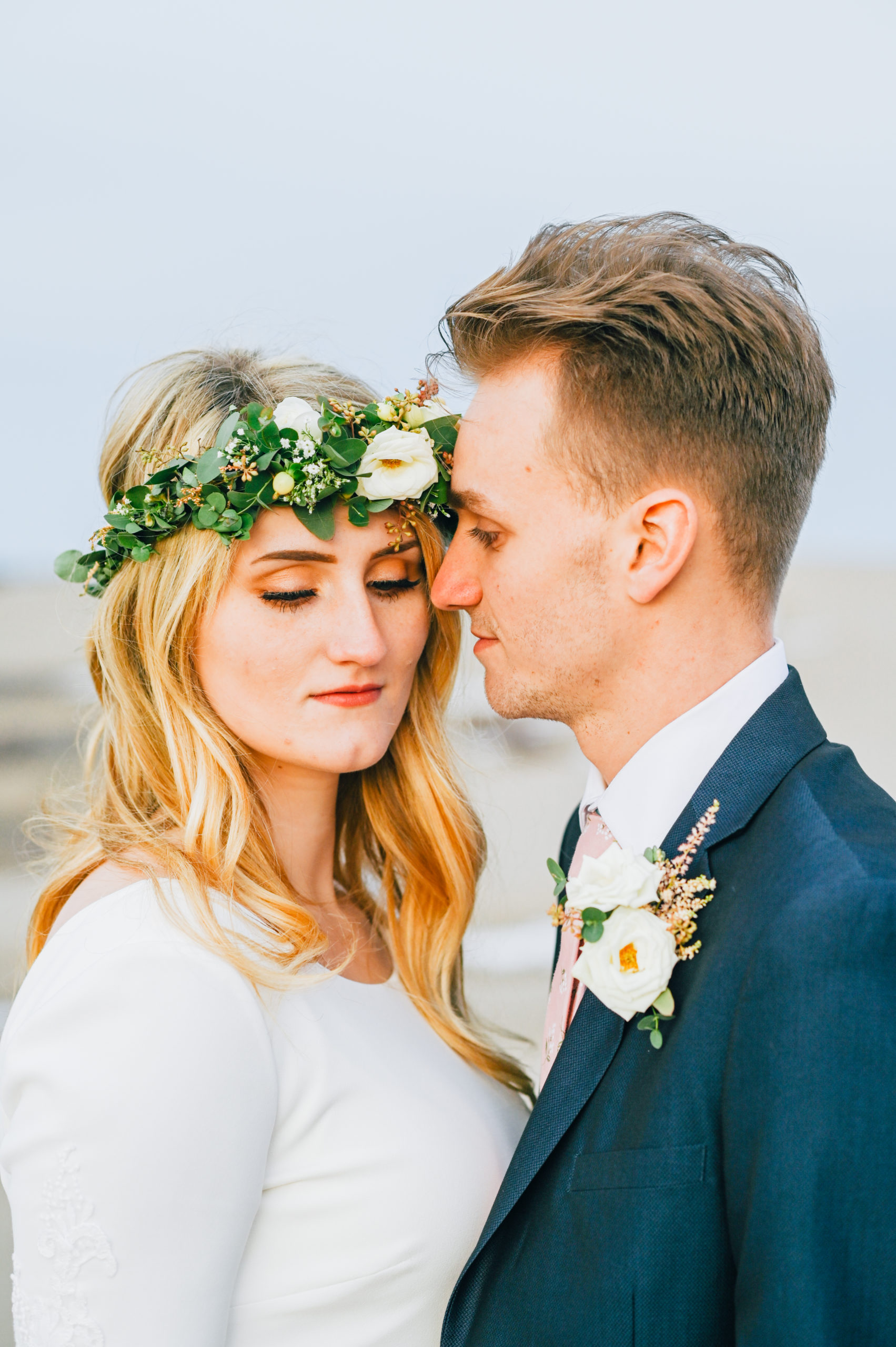 bride with green and white floral crown rests head on groom