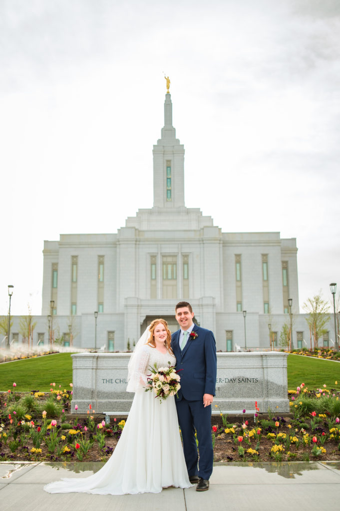 bride and groom standing in front of temple after getting married