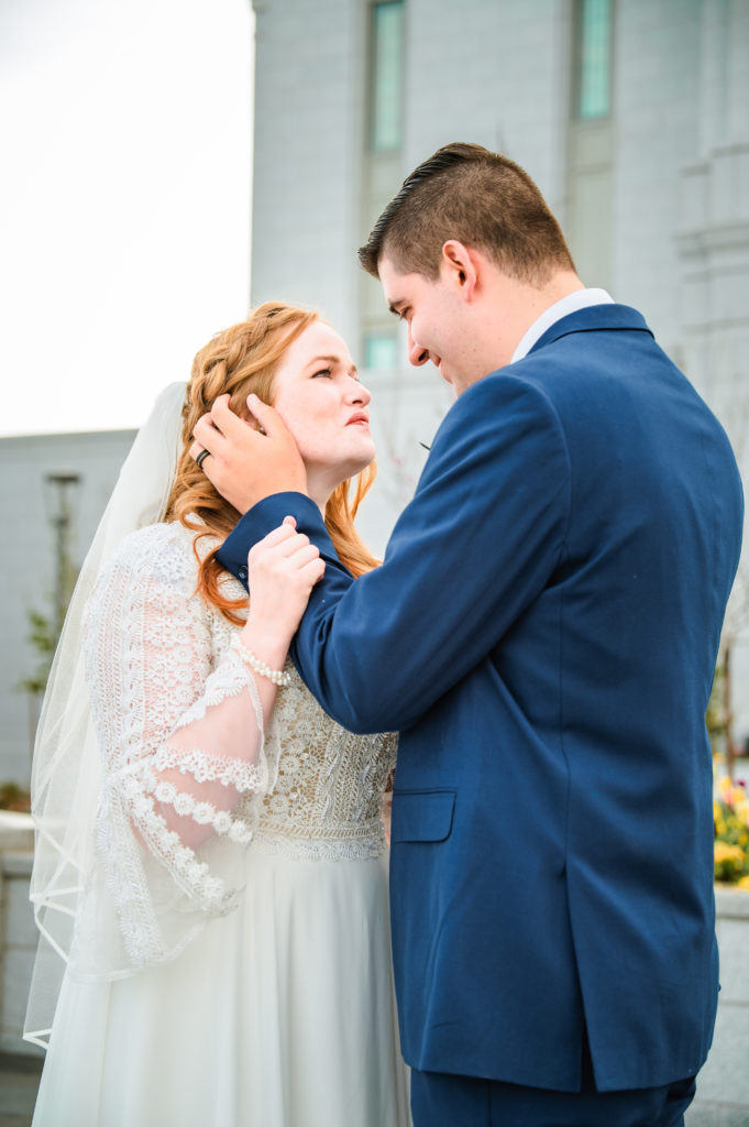 groom holding bride's face in front of pocatello temple