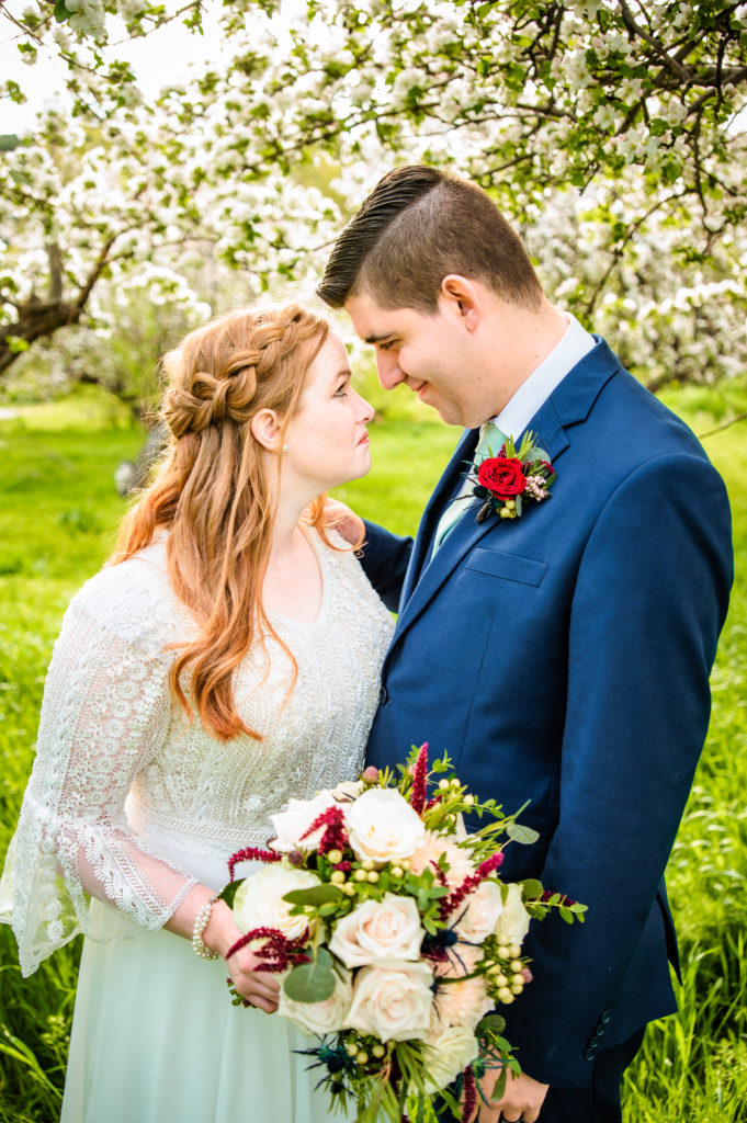 bride wearing lace dress with sleeves looking at groom in navy suit