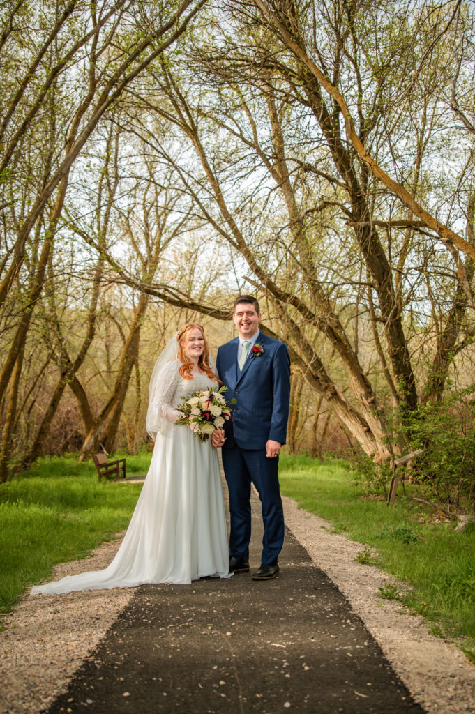 bride and groom standing together in trees during outdoor bridals