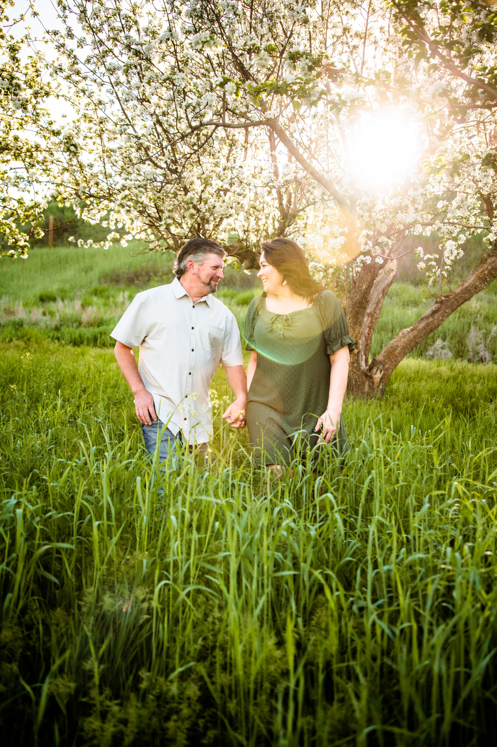 man and woman walking through field of tall green grass during Western Sunset Engagements