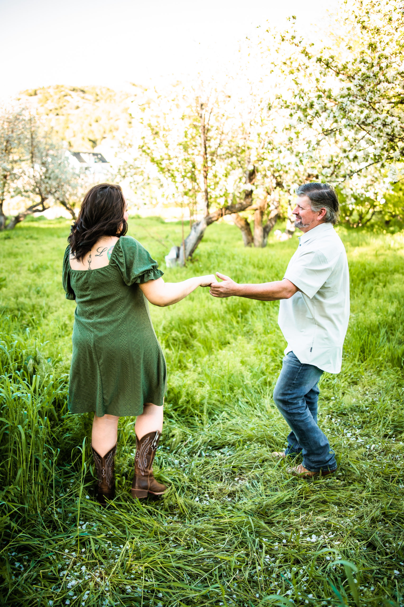 newly engaged couple dancing together in long green grass