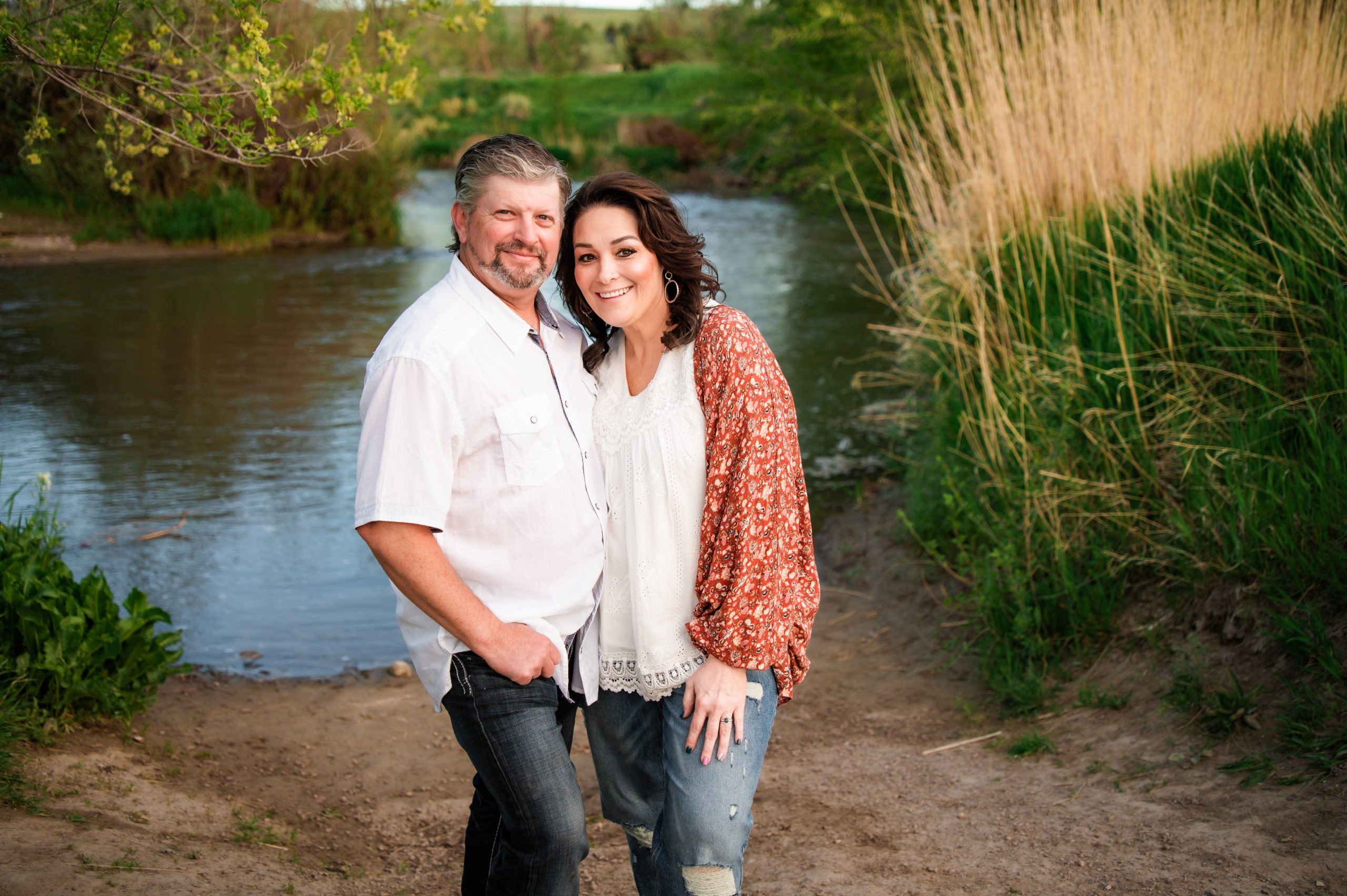 couple standing together by outdoor lake during Western Sunset Engagements