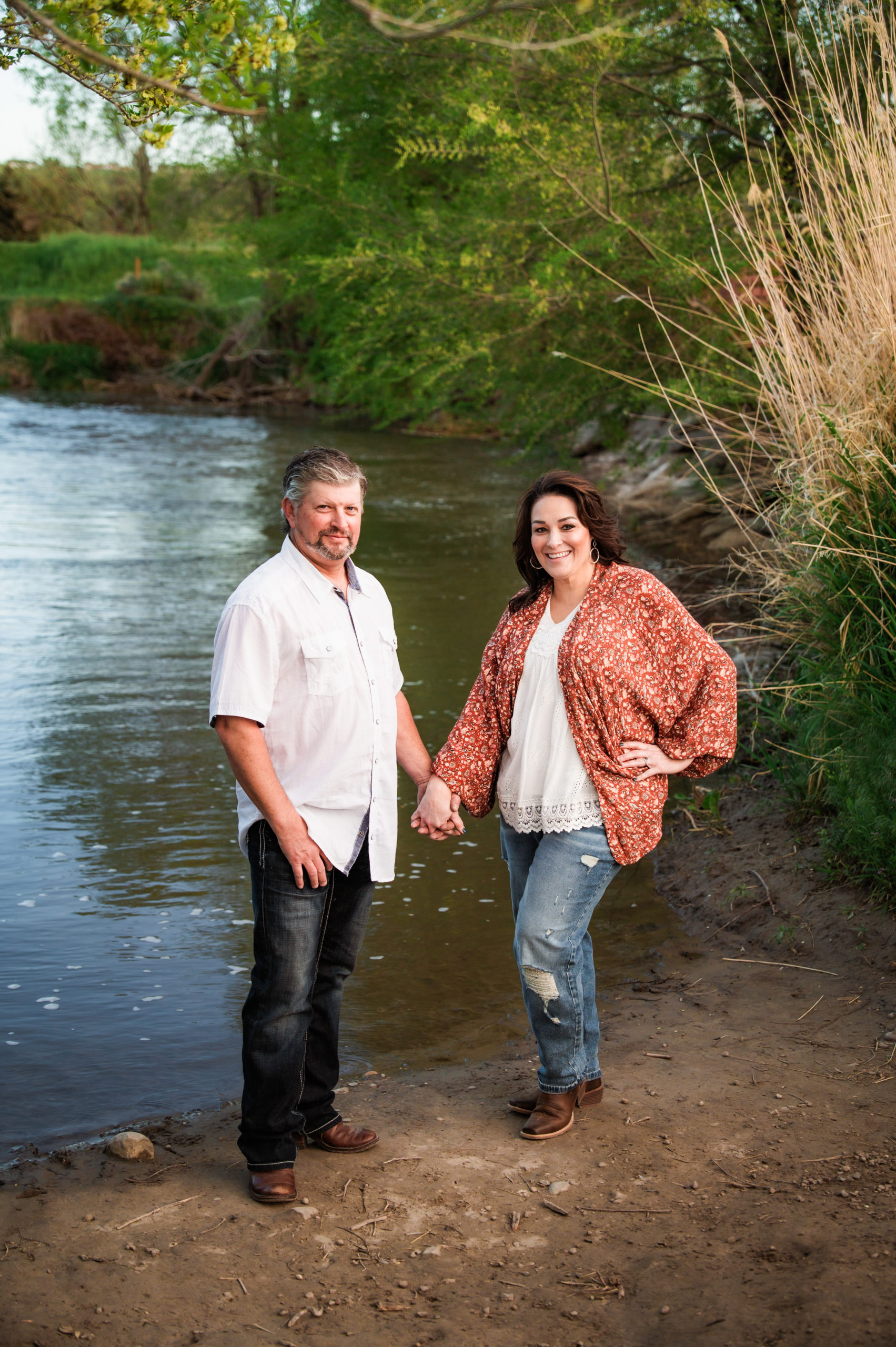 couple holding hands next to water