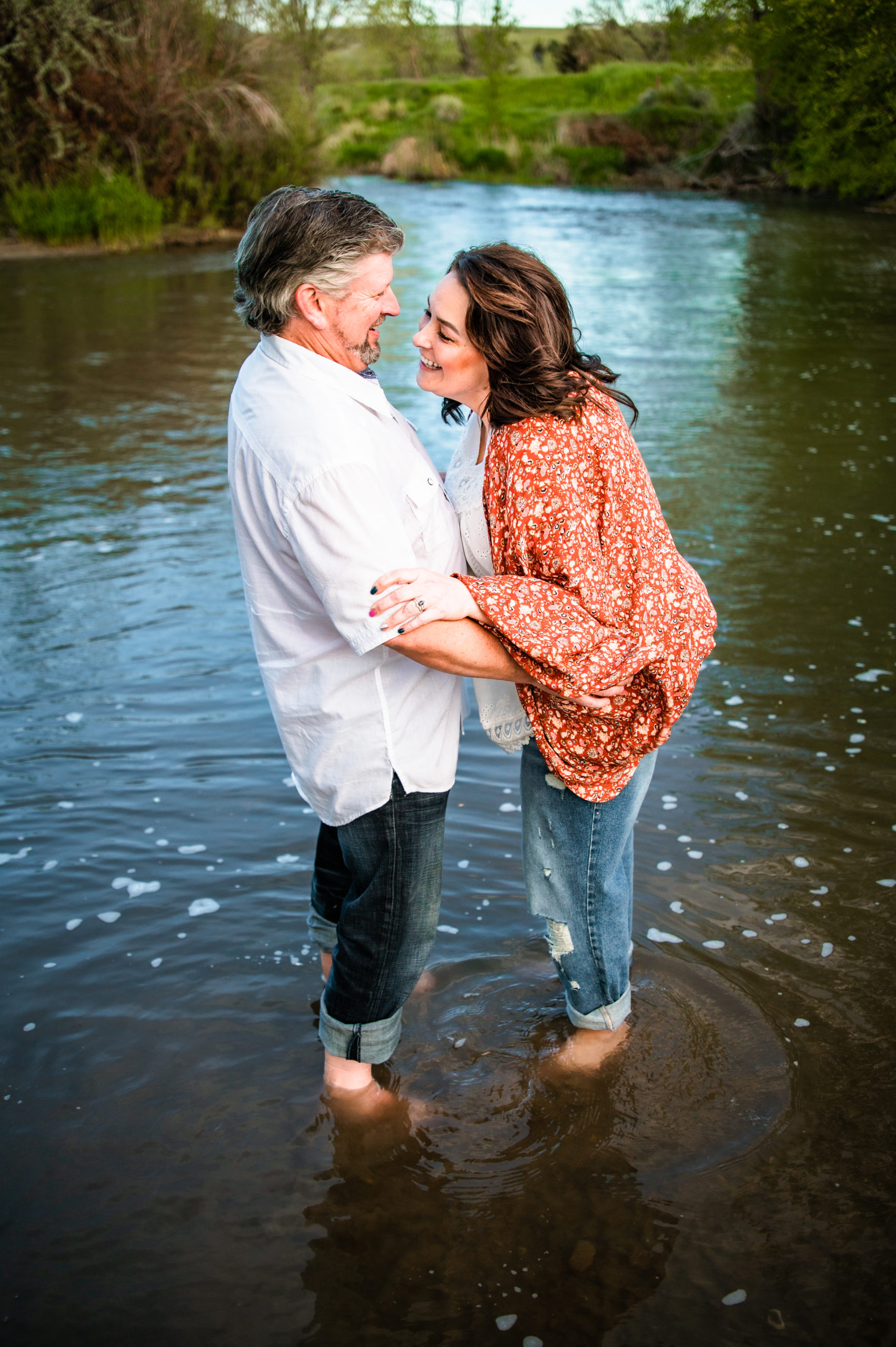 couple laughing in the water together during Western Sunset Engagements