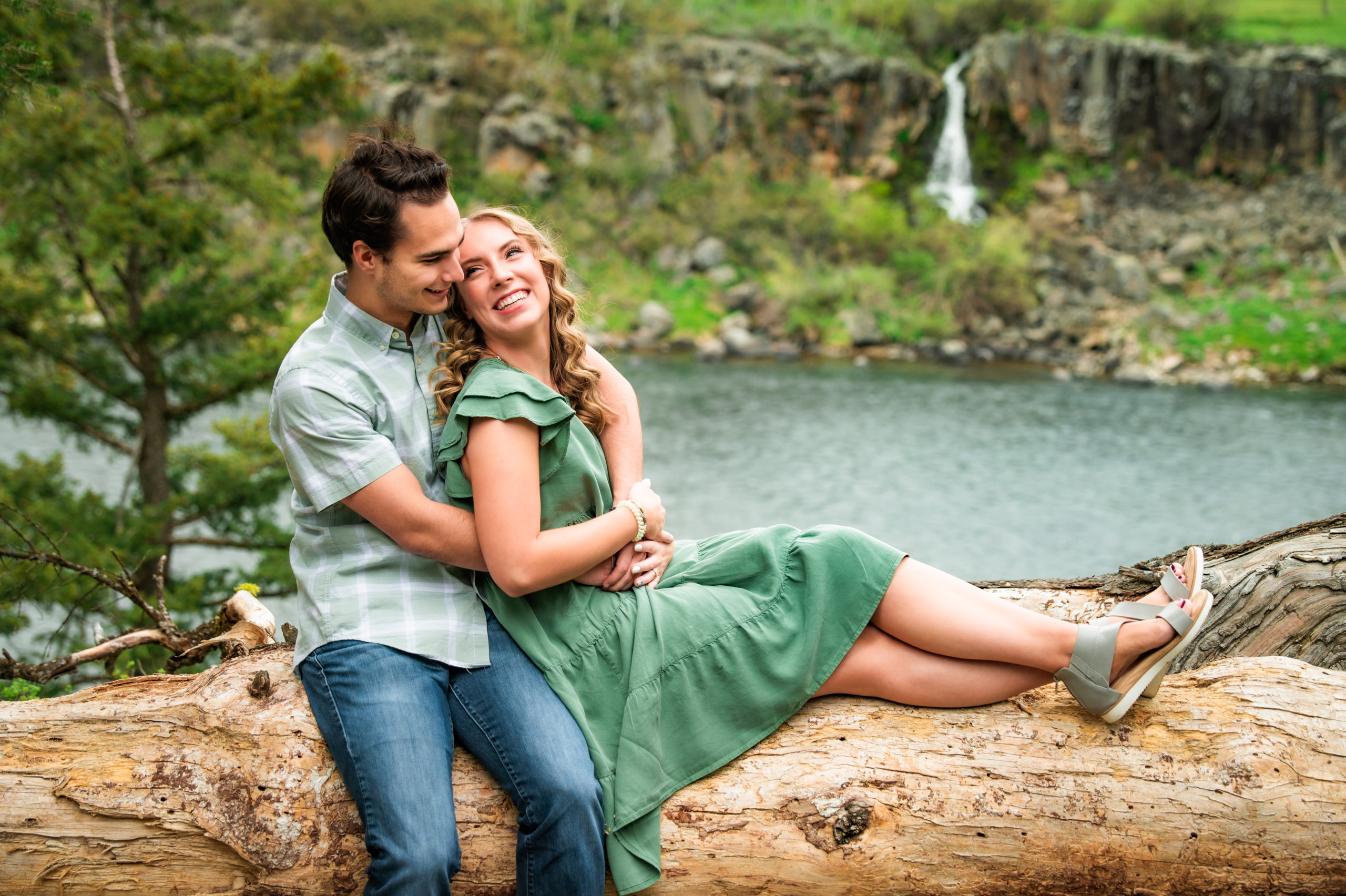 man and woman sitting on log during outdoor engagement session