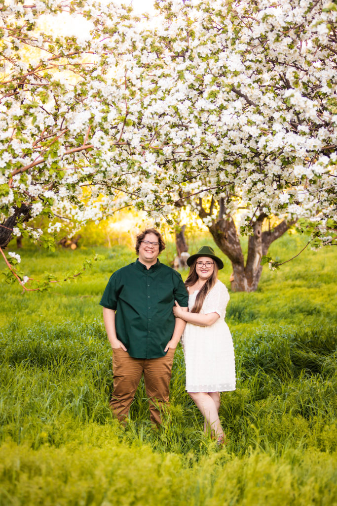 engaged couple holding hands in apple blossom during outdoor engagement photos