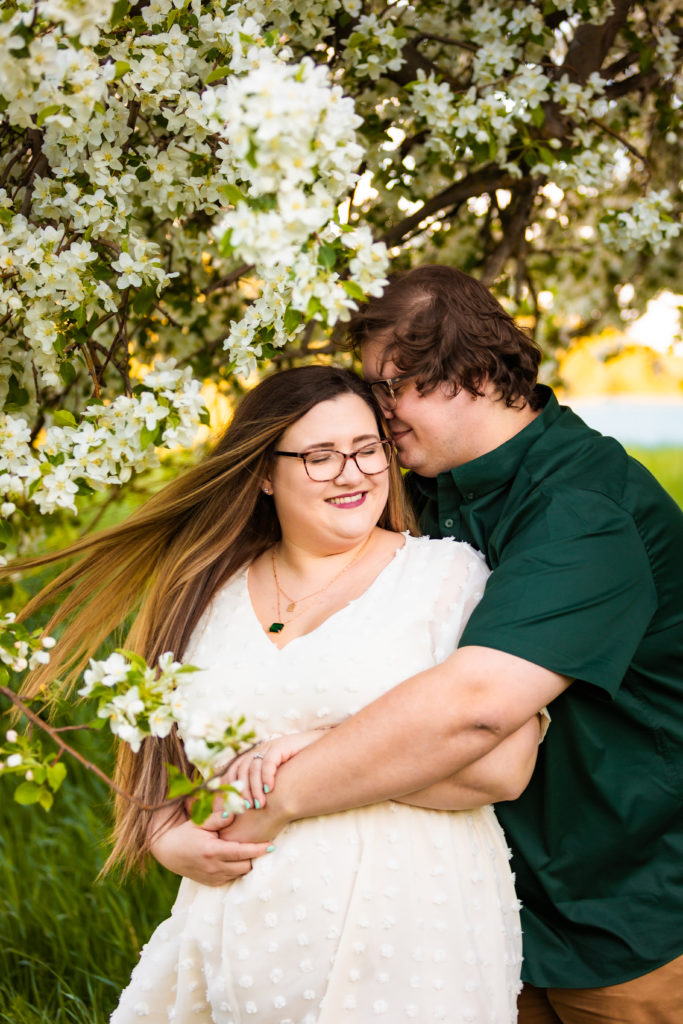 man nuzzling into woman's hair during apple blossom portraits
