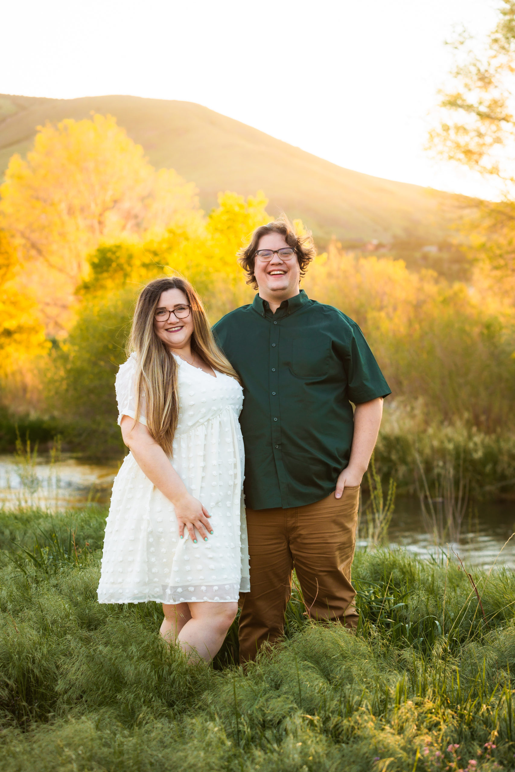 woman with long brown hair wearing white dress smiling during pocatello engagements with man wearing olive green shirt