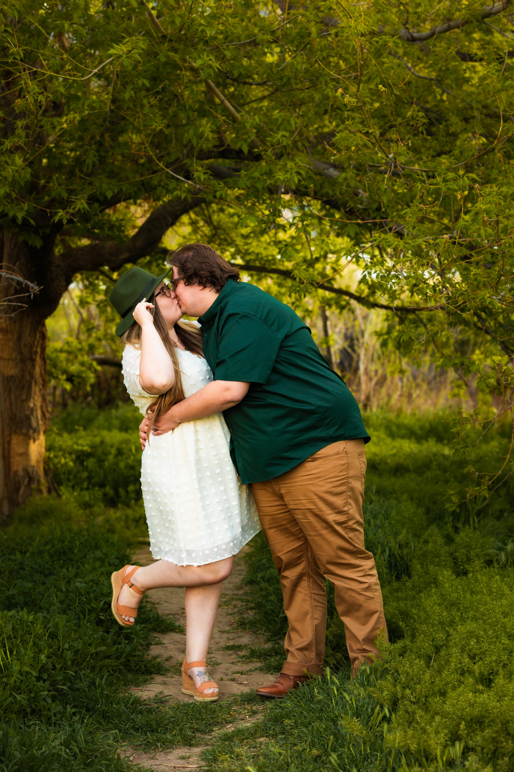 newly engaged couple kissing and laughing in forest