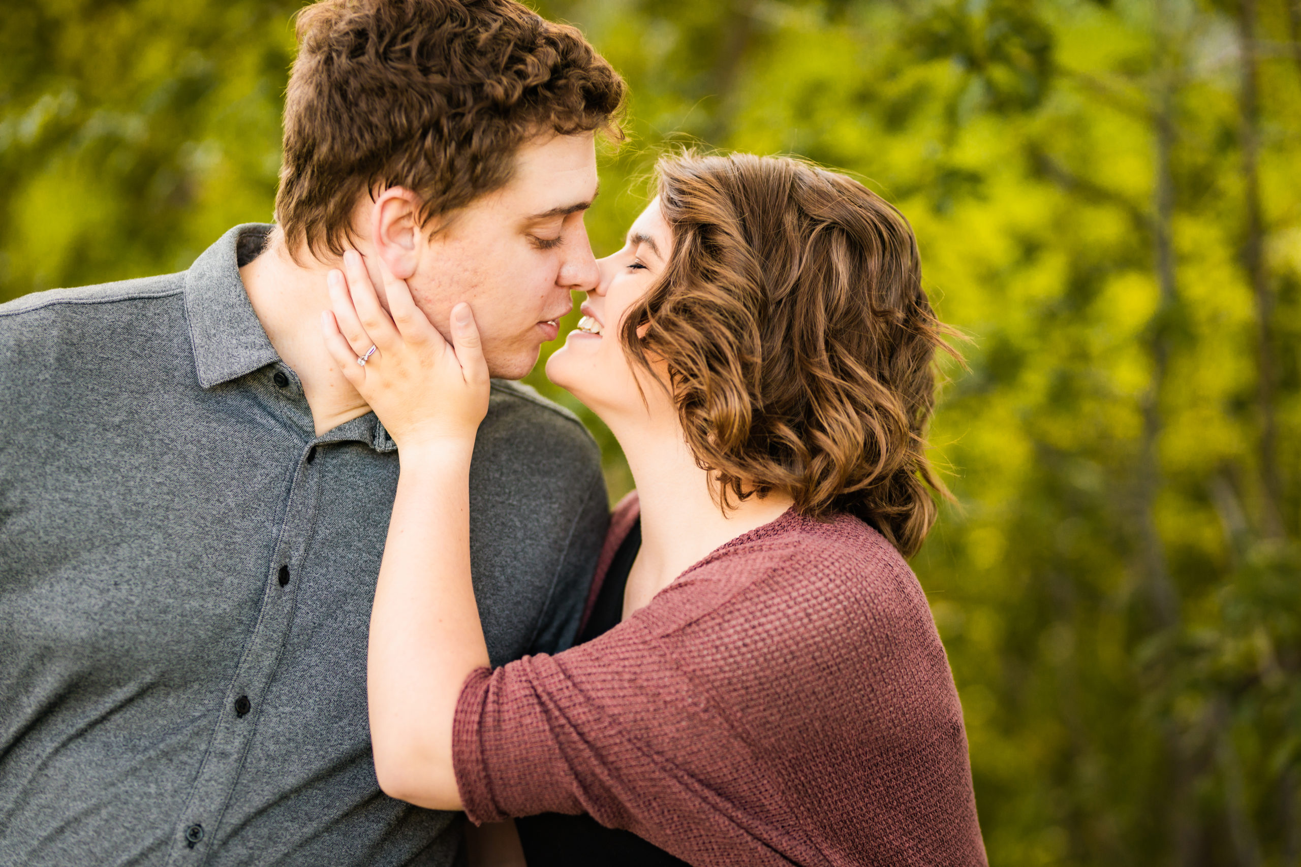 woman placing hand on man's cheek kissing during Pocatello Apple Blossom Engagements