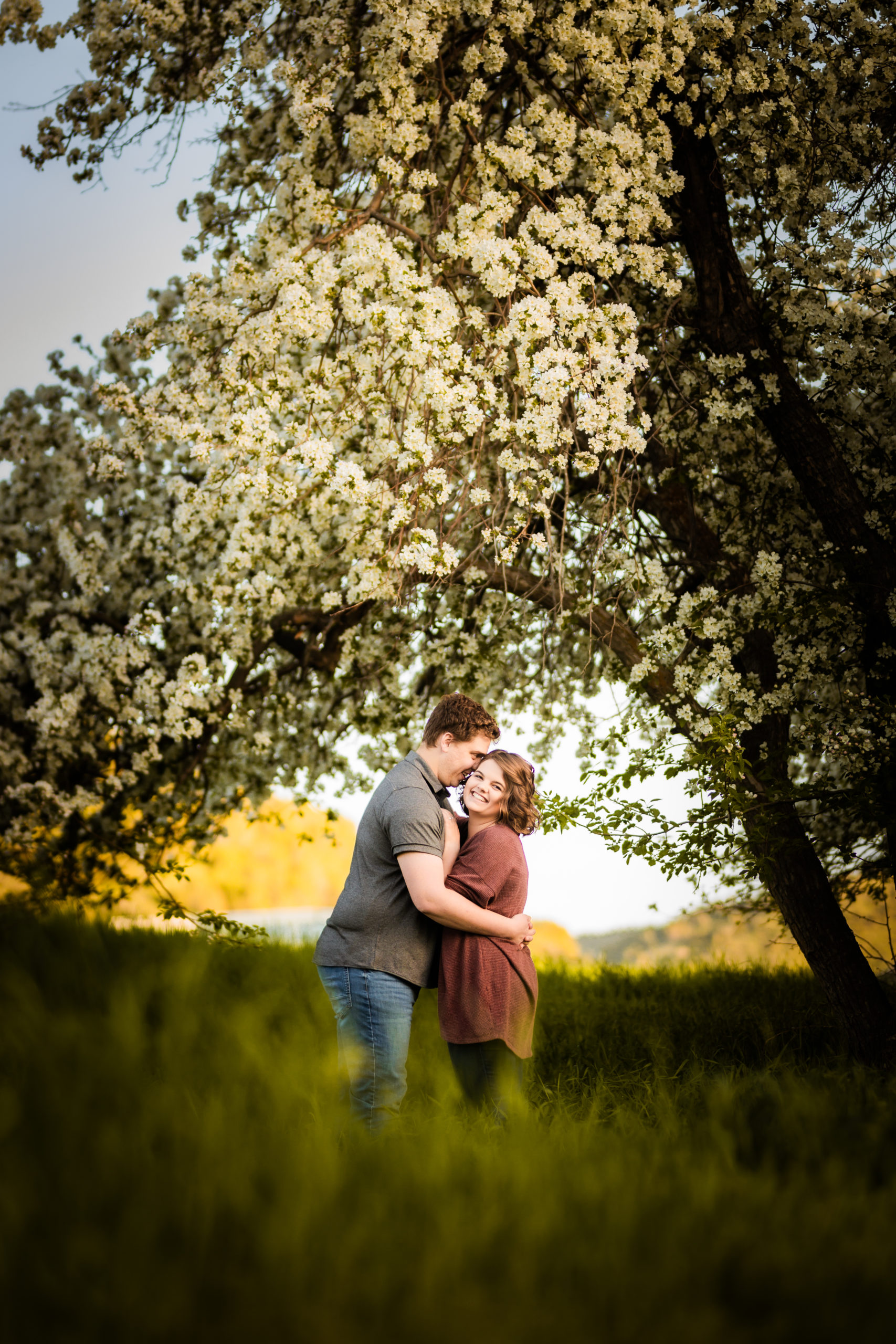 man whispering in woman's ear during engagement photos
