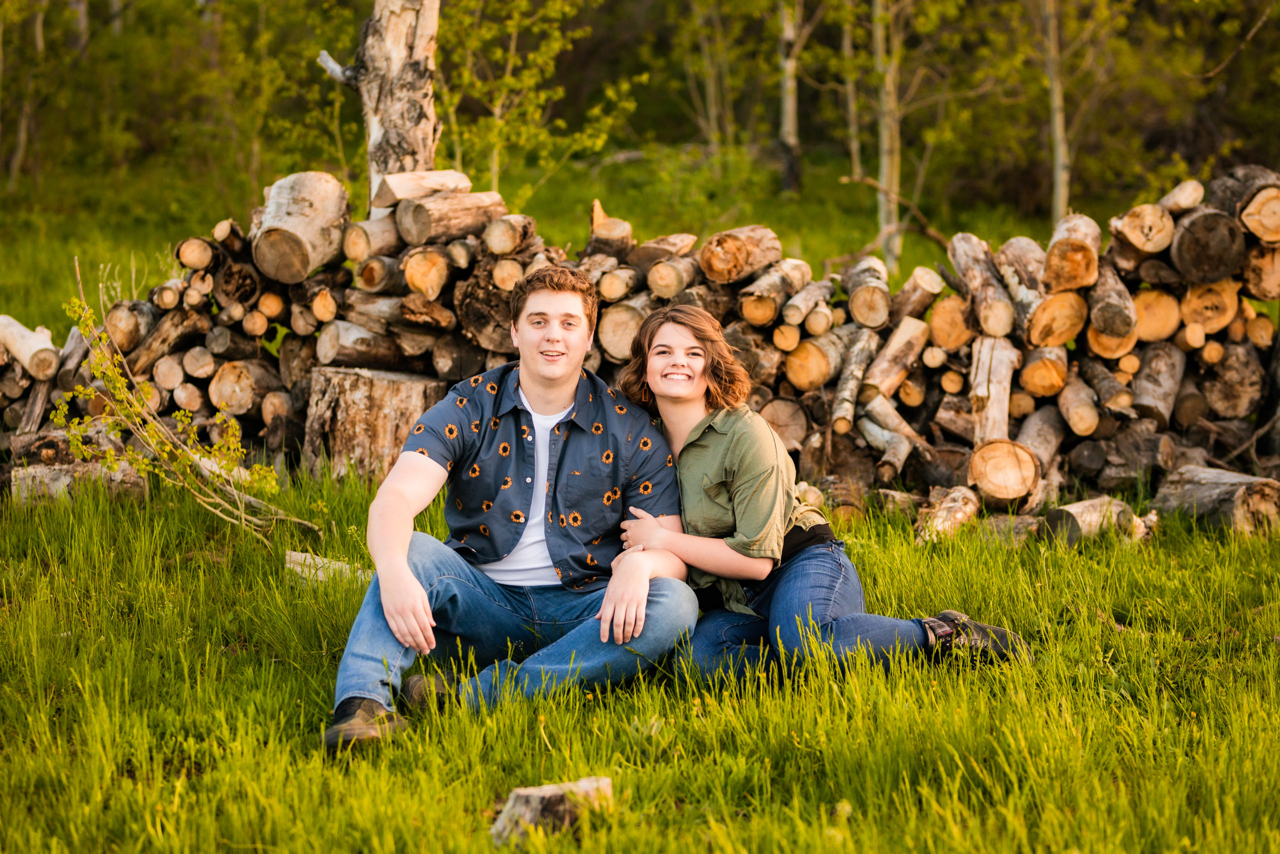 engaged couple sitting in grass during outdoor engagements