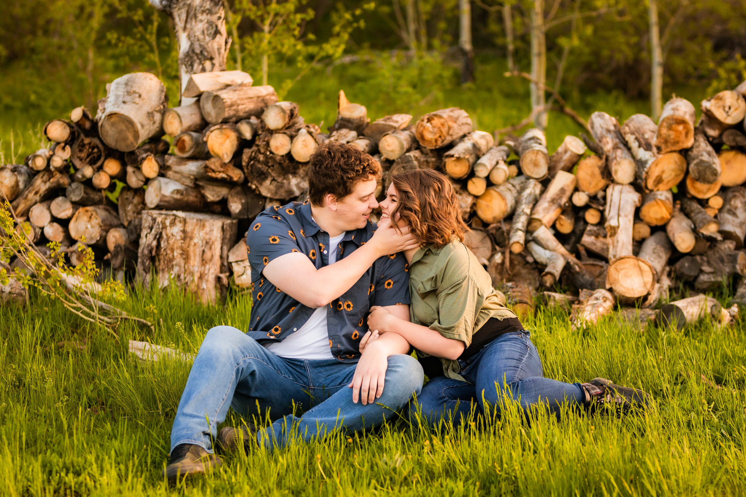 couple sitting on ground in front of logs of wood