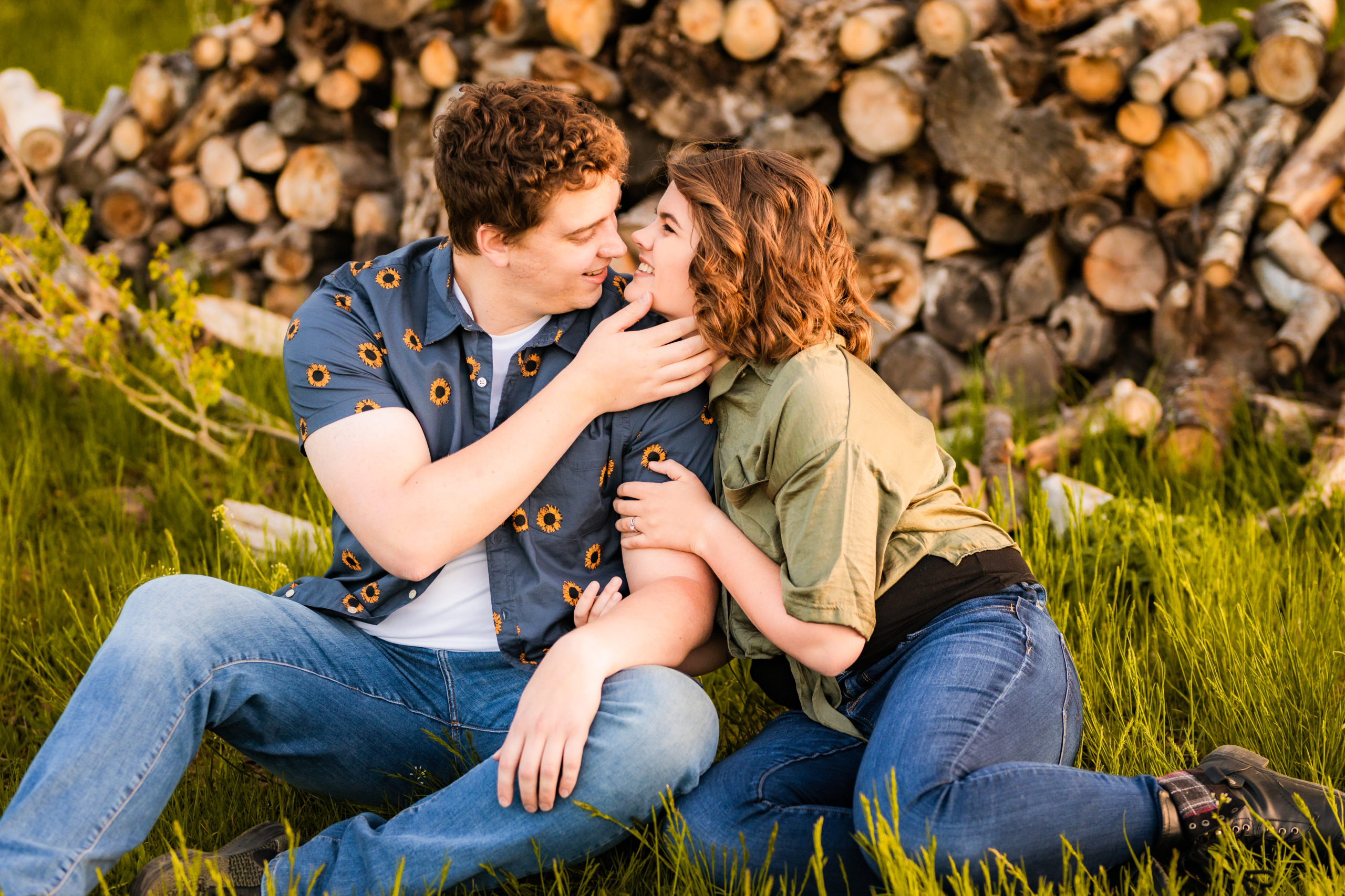 newly engaged couple kissing at pile of wood during Sunflower Pocatello Engagements