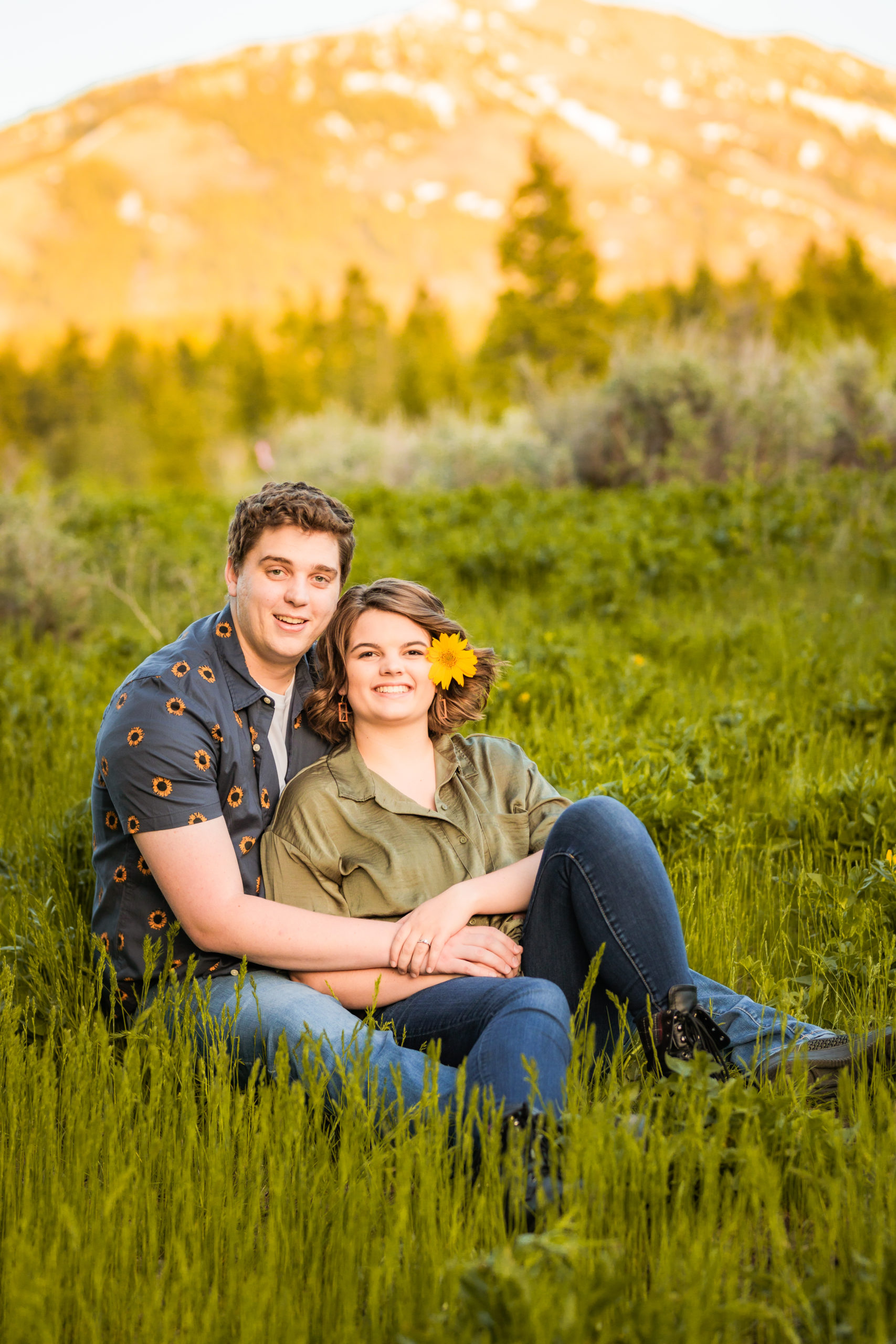 newly engaged couple sitting in field of grass during engagements