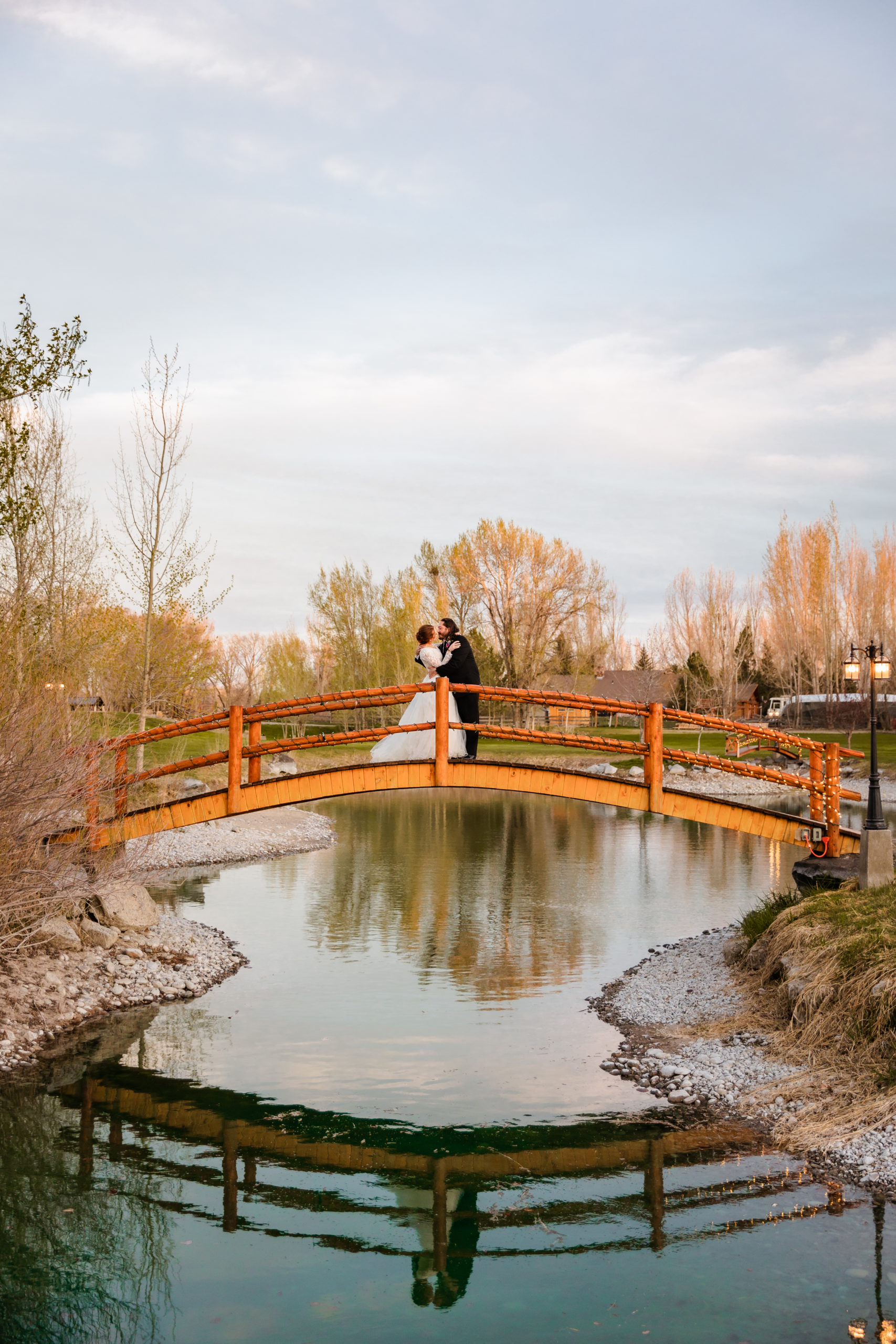 bride and groom kiss while standing on a bridge at Labelle Lake wedding venue