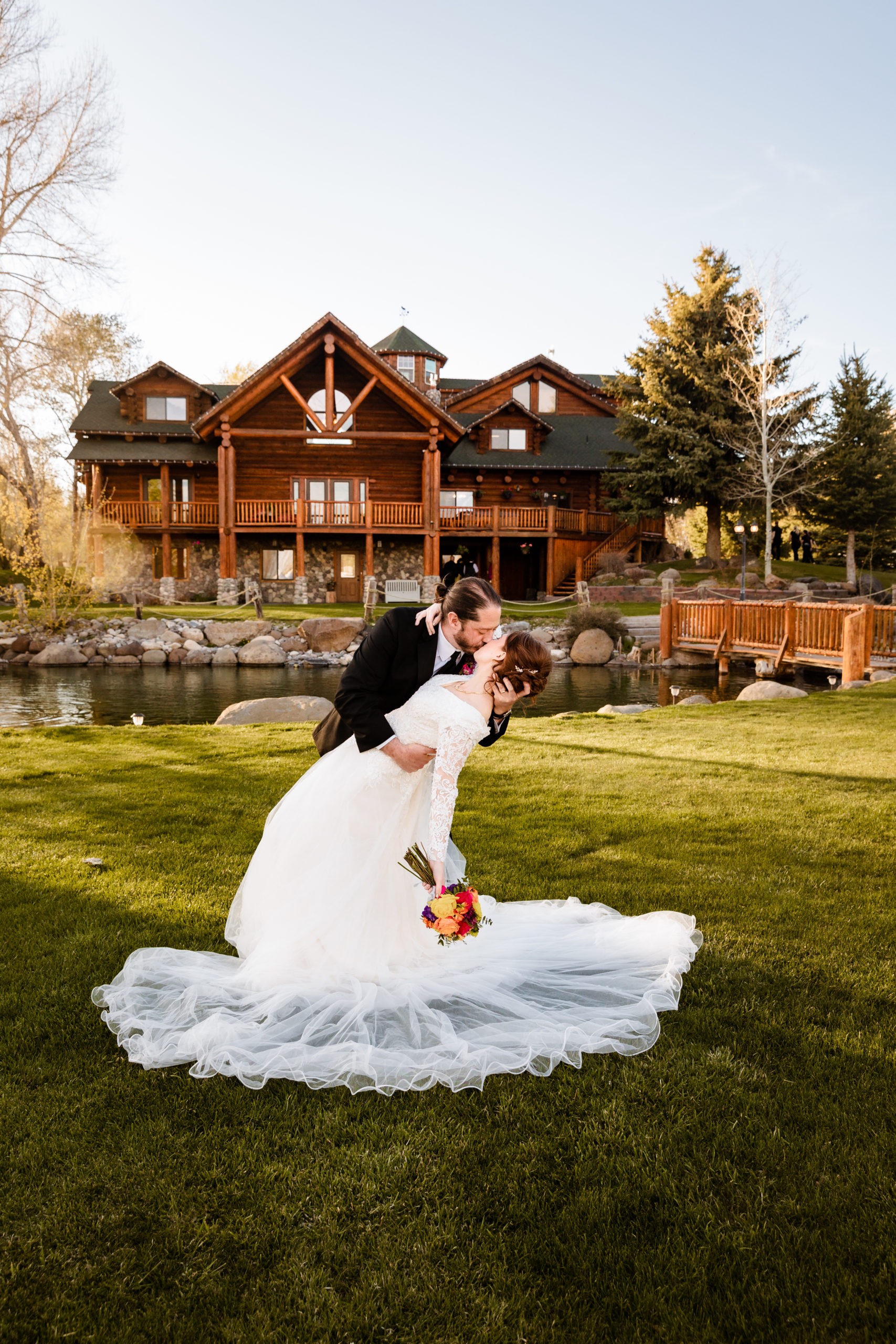groom dips his bride back as he kisses her in front of their wedding cabin venue