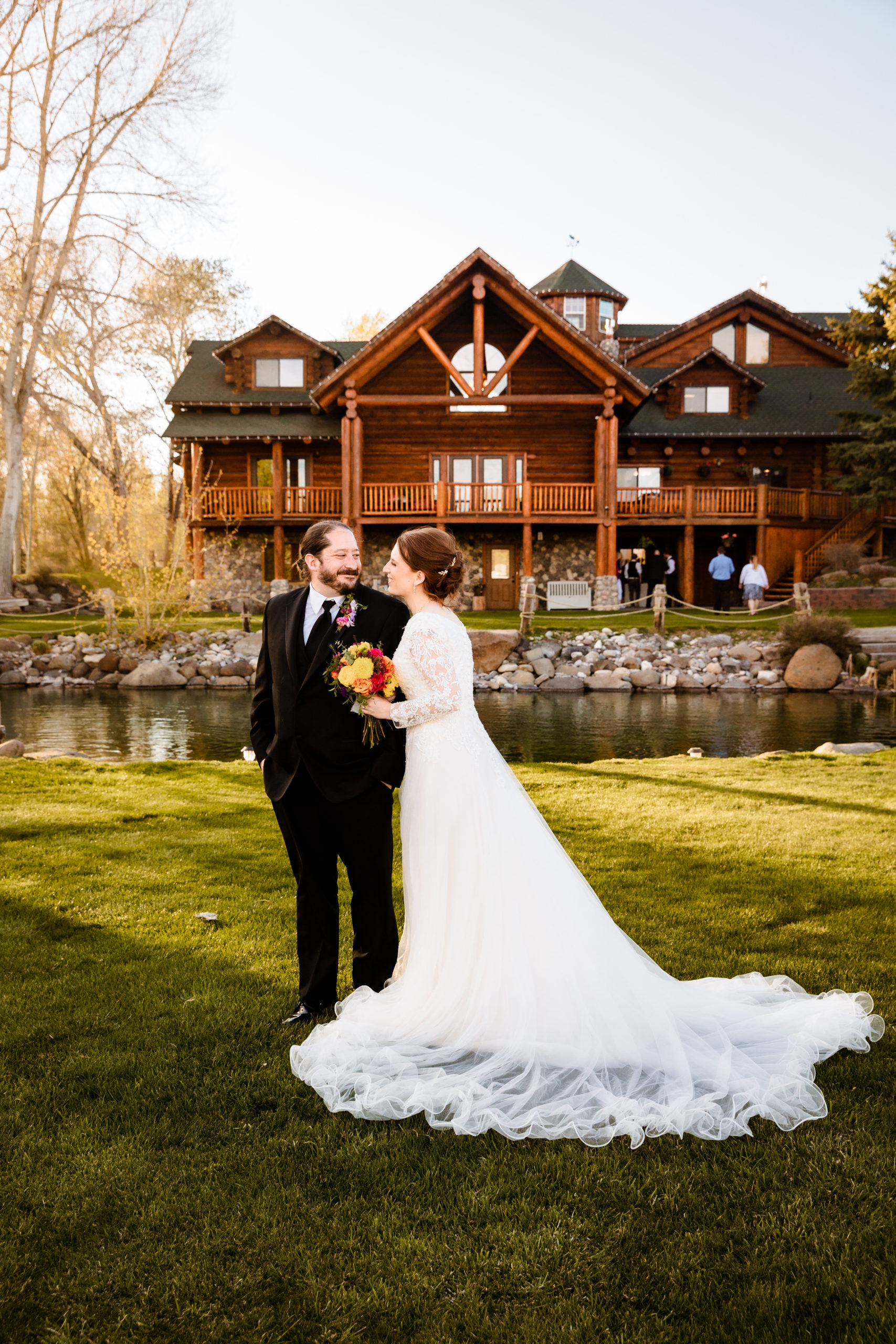 Labelle Lake wedding venue cabin and small lake behind bride and groom as they pose for their wedding portraits