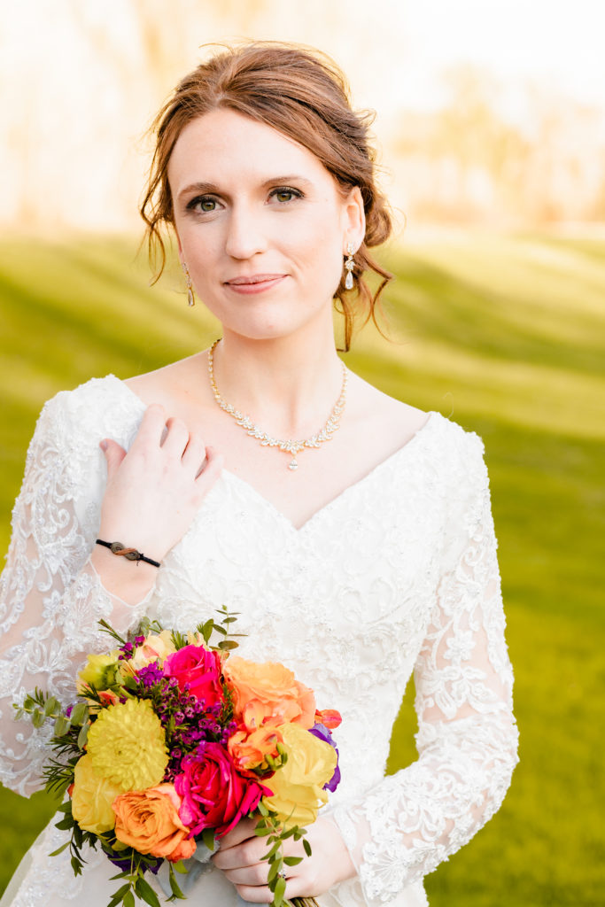 fall wedding at Labelle Lake Idaho with bride in a lace long sleeve wedding dress holding a bridal bouquet of warm hues