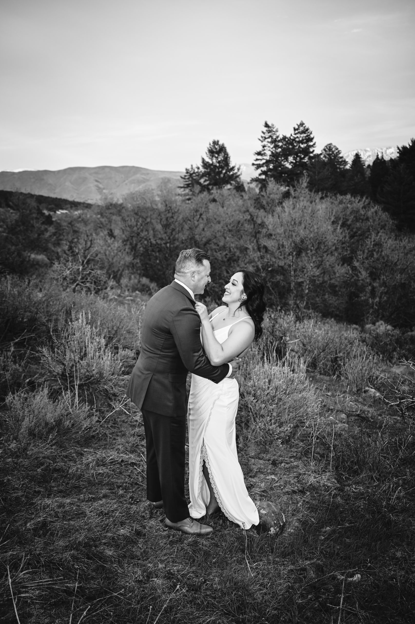outdoor wedding photos with bride adn groom hugging in a field and laughing captured by Pocatello wedding photographer