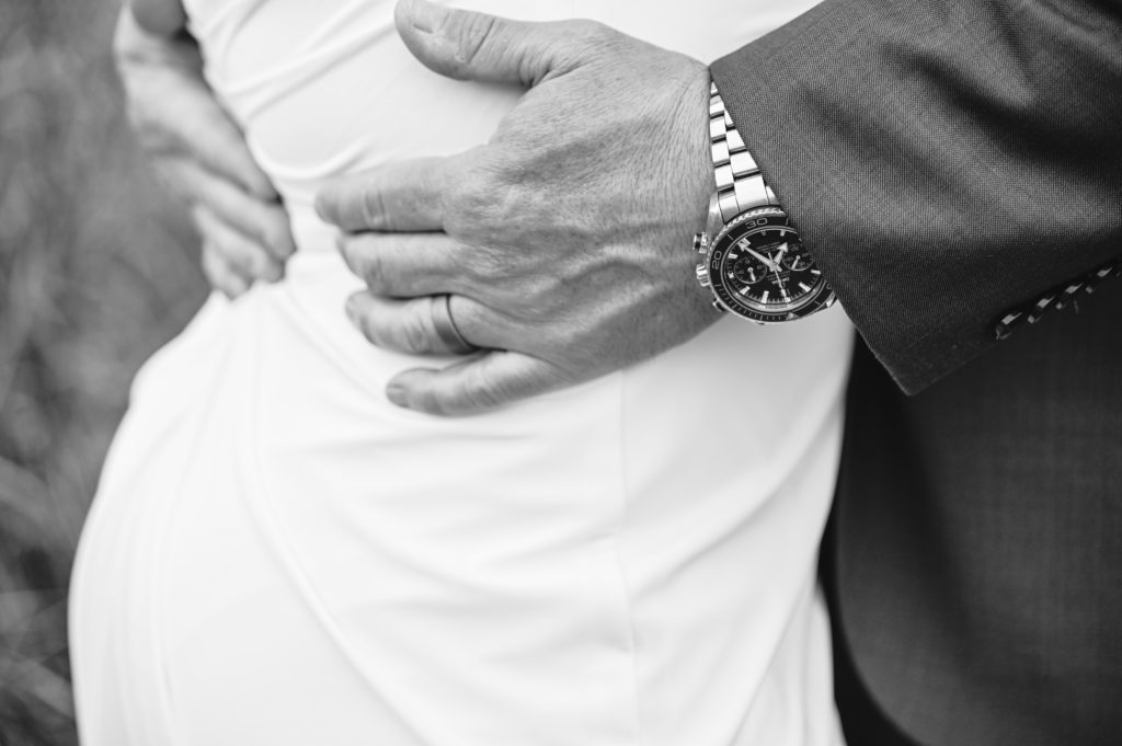 detail shot of grooms hand holding his brides waist