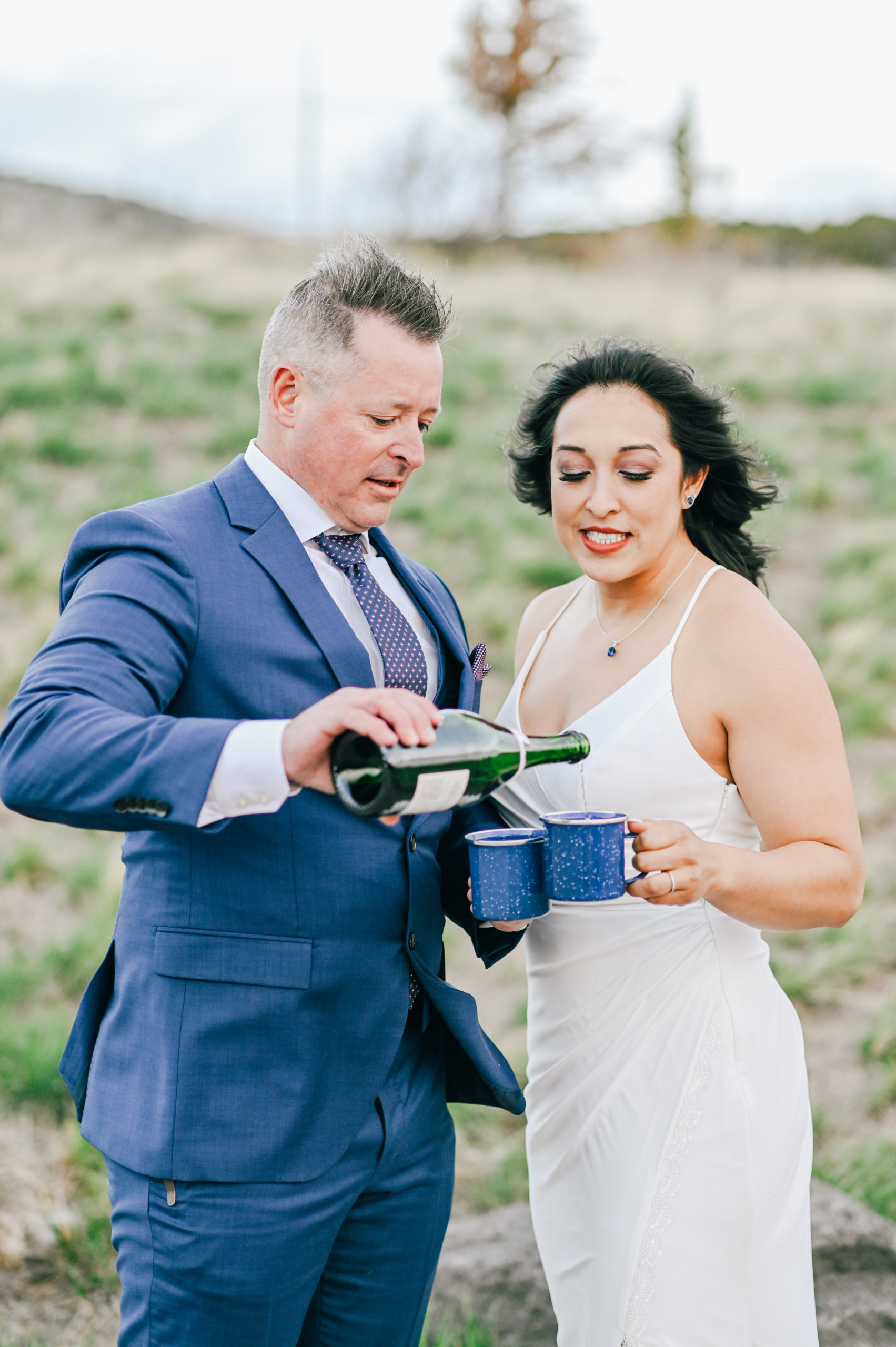 groom pouring champagne into two travel mug for himself and his bride captured Pocatello wedding photographer
