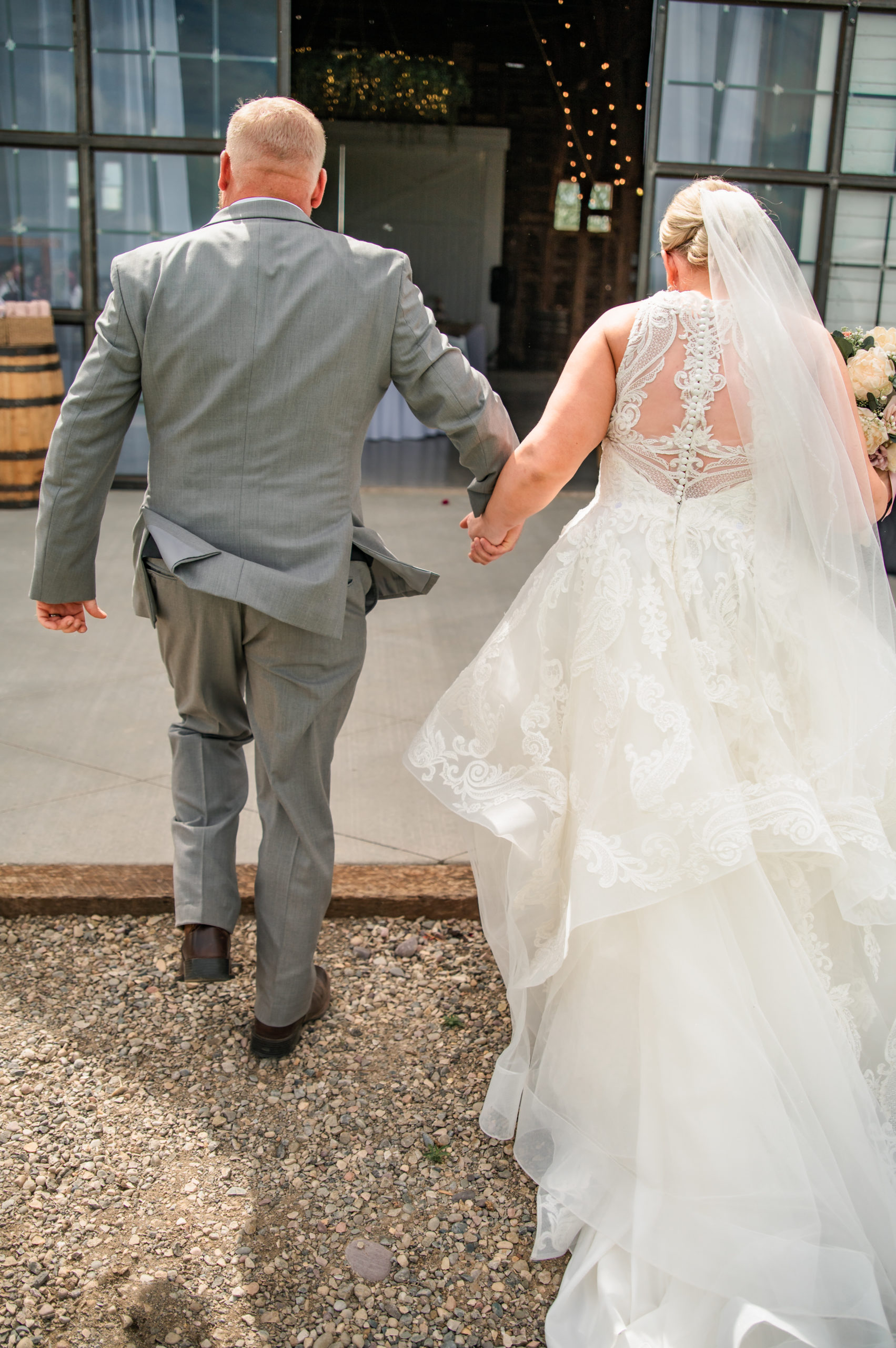 bride and groom holding hands and walking into their barn wedding venue for their reception in Pocatello