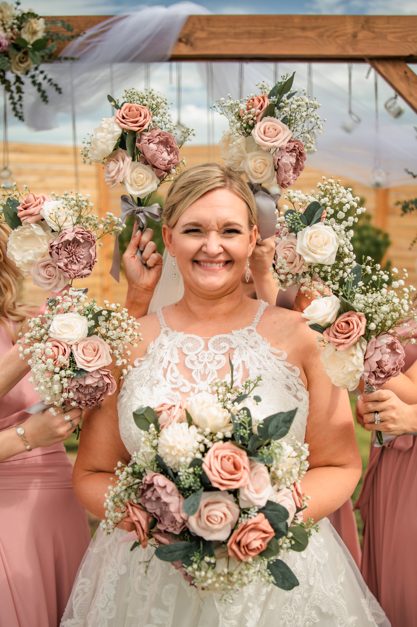 bride holding her flower bouquet as her bridesmaids hold they bouquets around her head