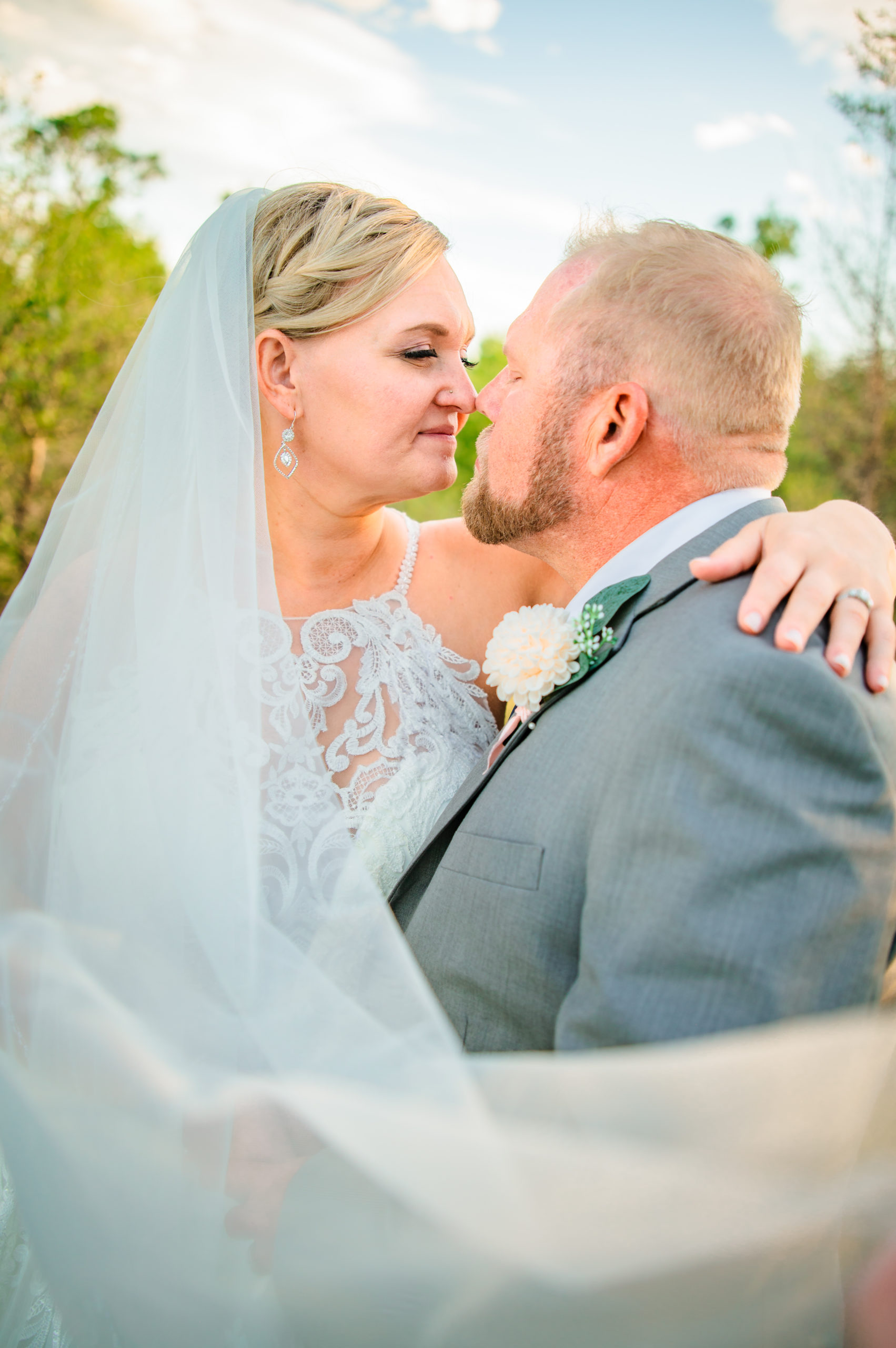 Pocatello wedding photographer captures bride sitting on grooms lap and holding her arm around his shoulder while their noses touch