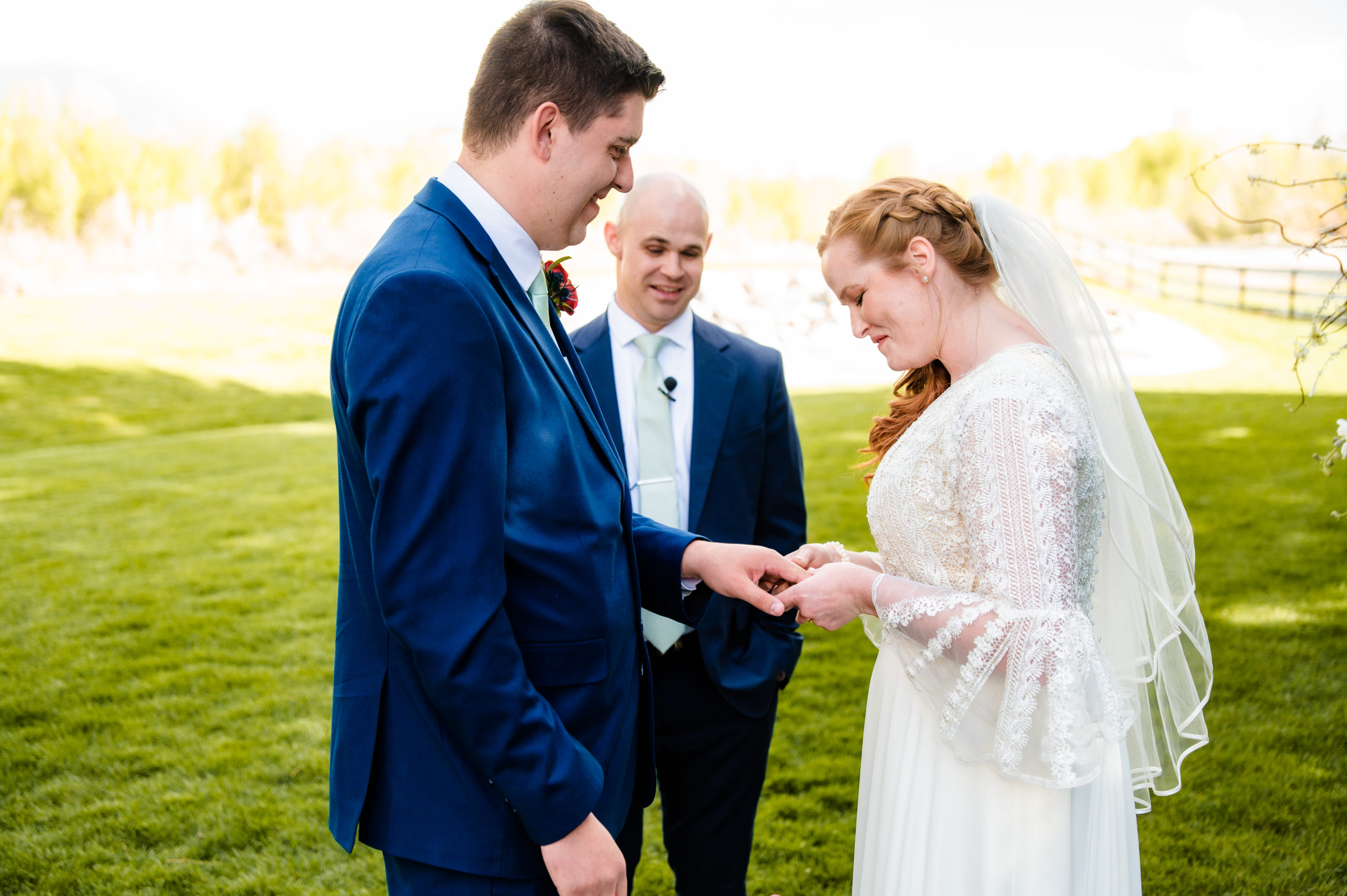 bride putting on grooms wedding band on his hand as she says her vows
