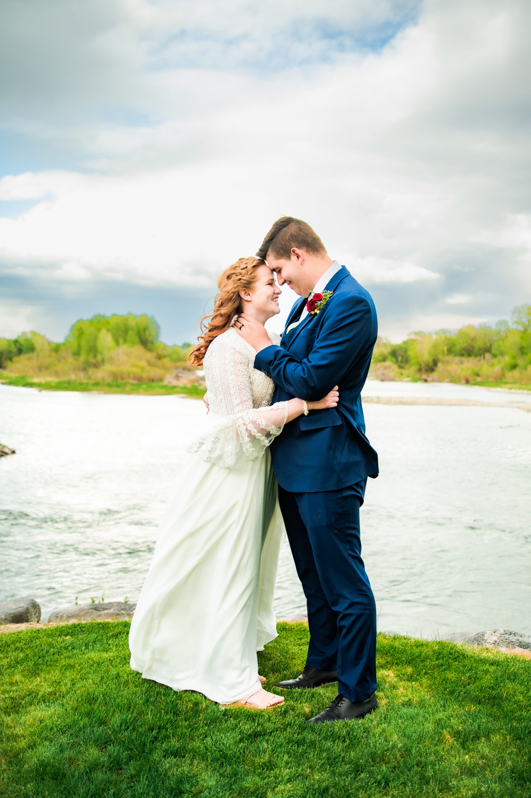 bride and groom snuggle noses next to rose river a wedding venue in blackfoot idaho next to the river