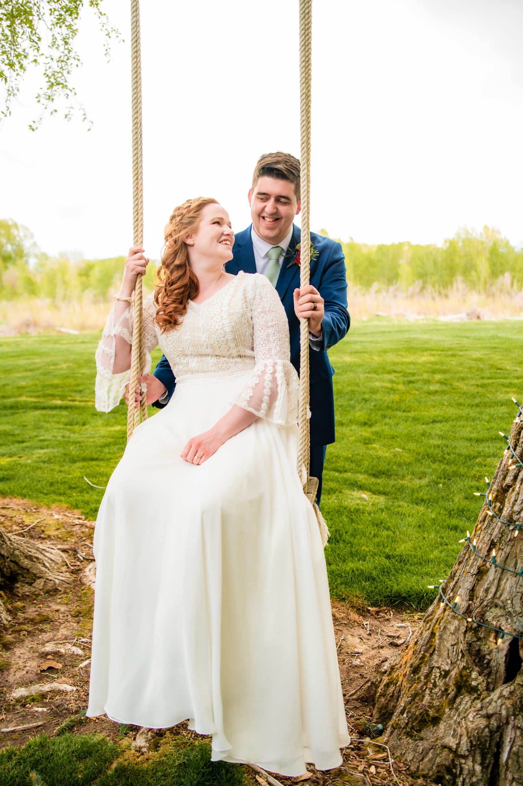 bride laughs while groom pushes her on swing at blackfoot wedding venue rose river receptions