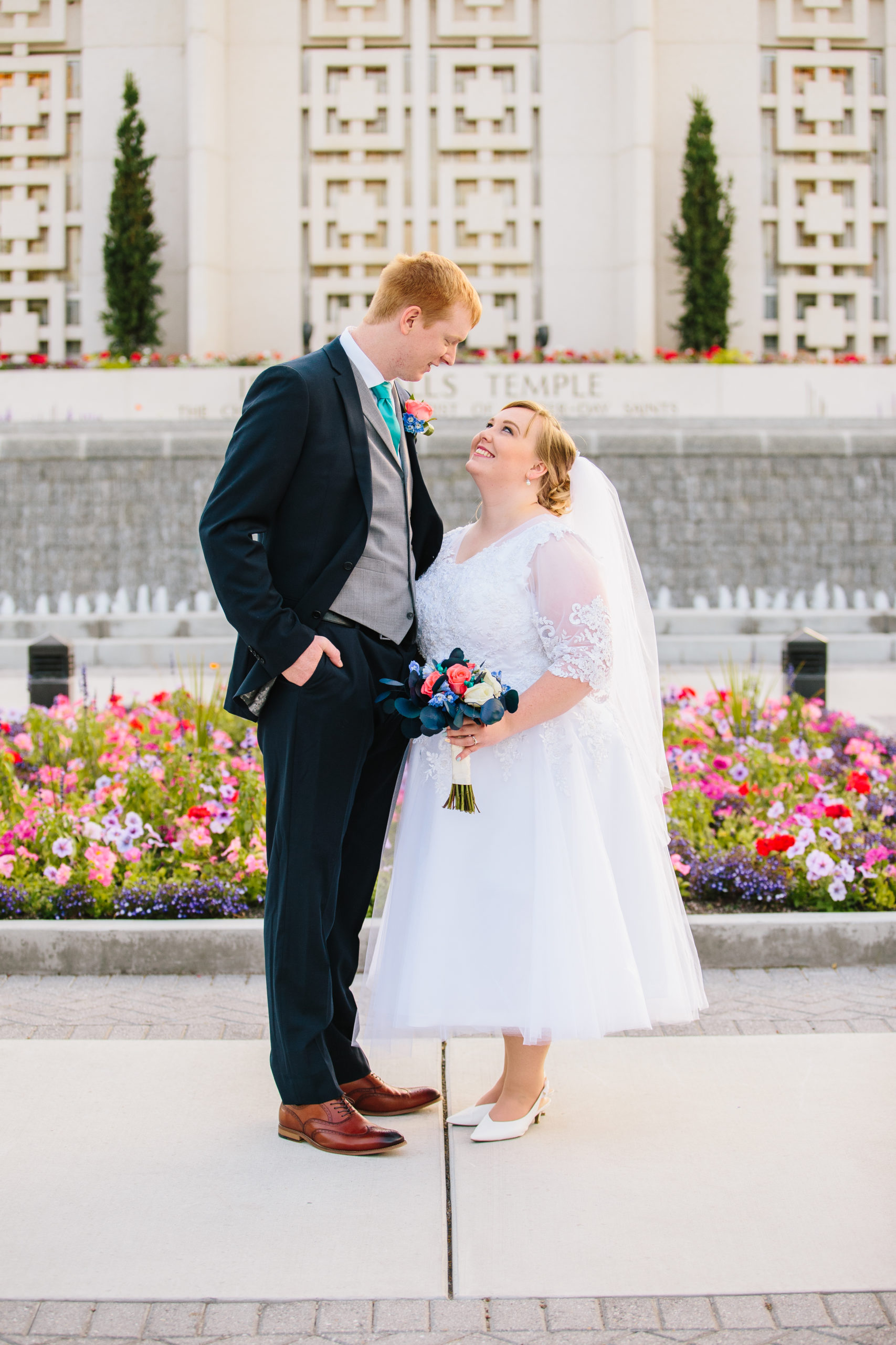 short bride looking up at tall ginger groom in front of flowers Idaho Falls Temple Wedding Tips