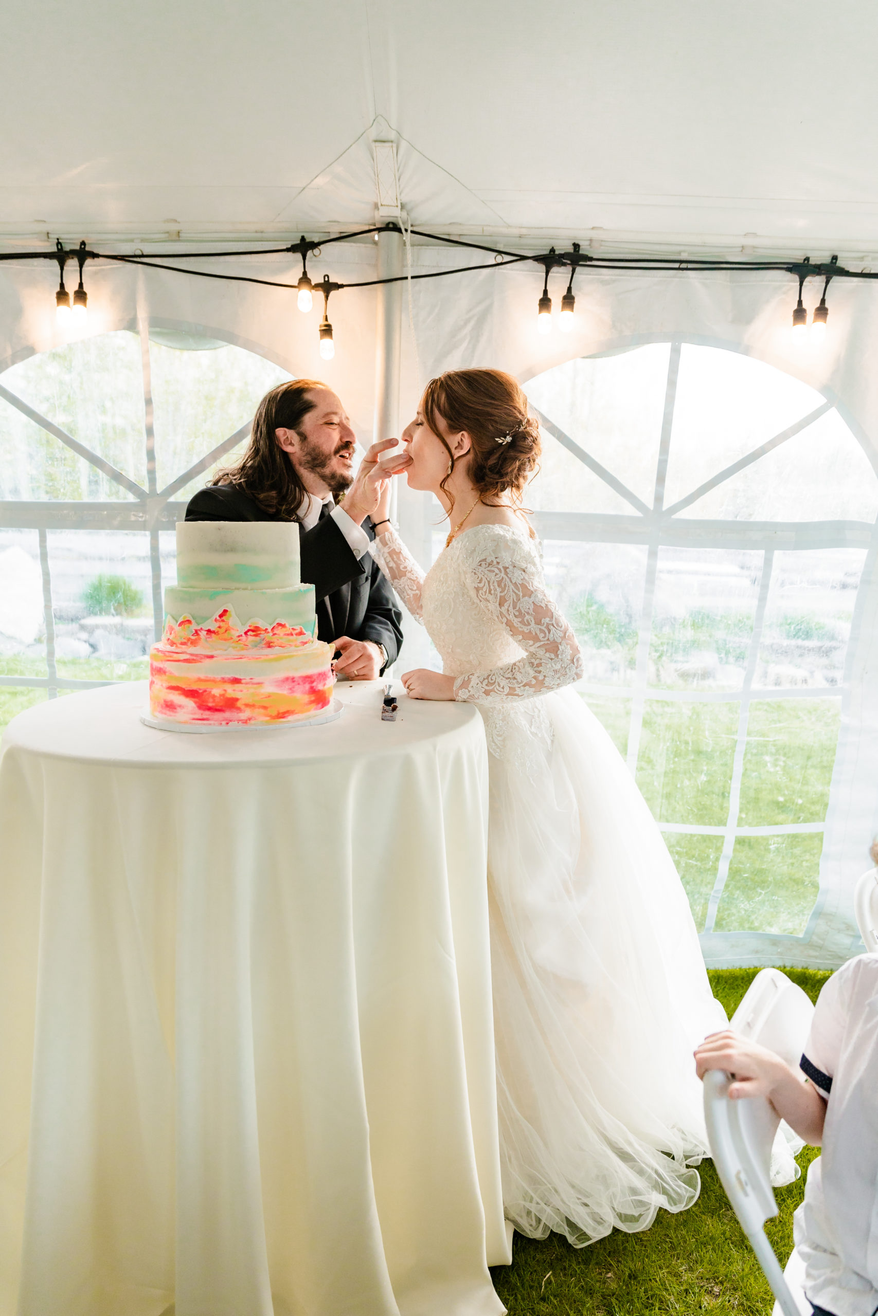 bride and groom cut the cake at their Idaho Falls wedding in a tent