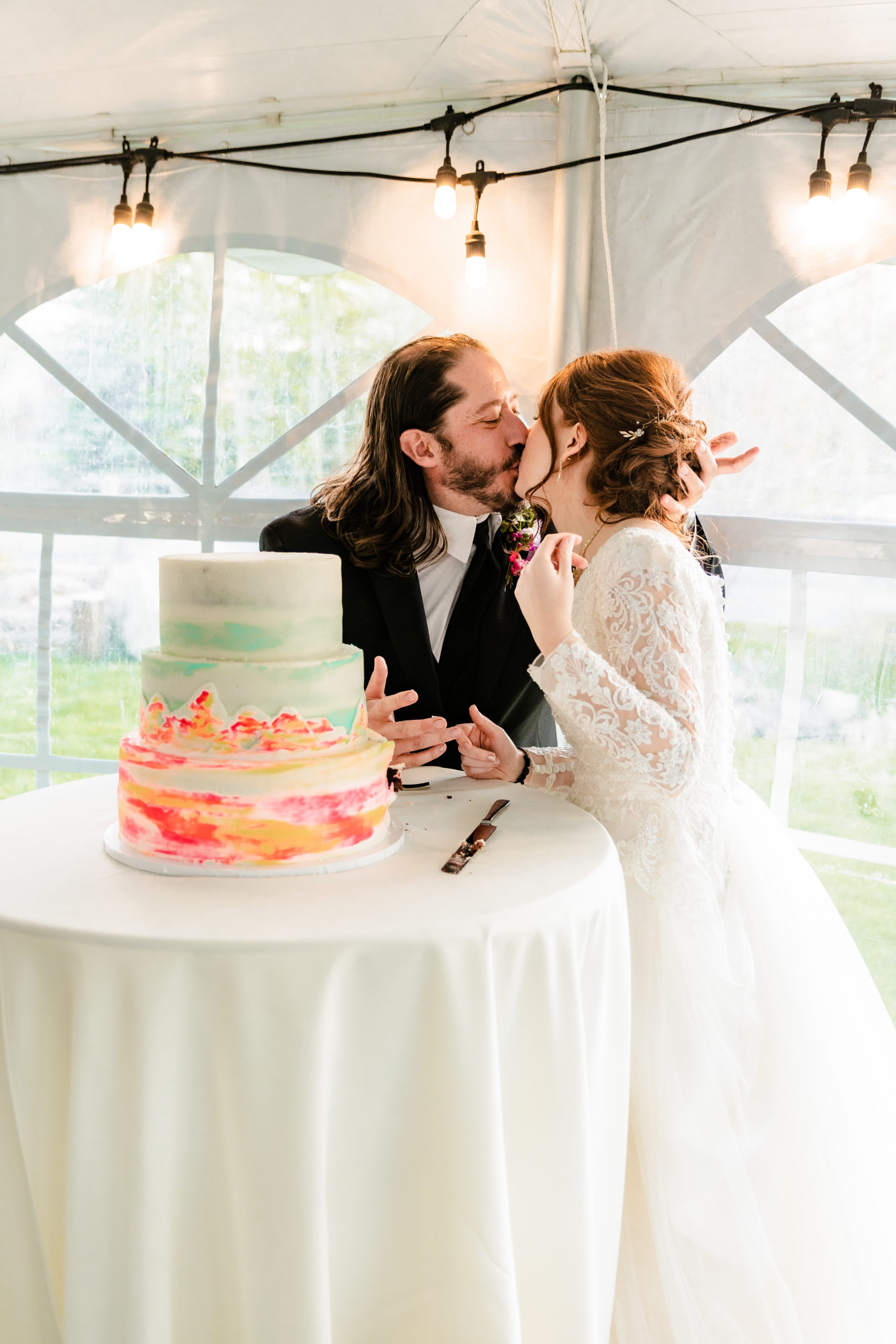 bride and groom kissing after cutting cake as newly married couple
