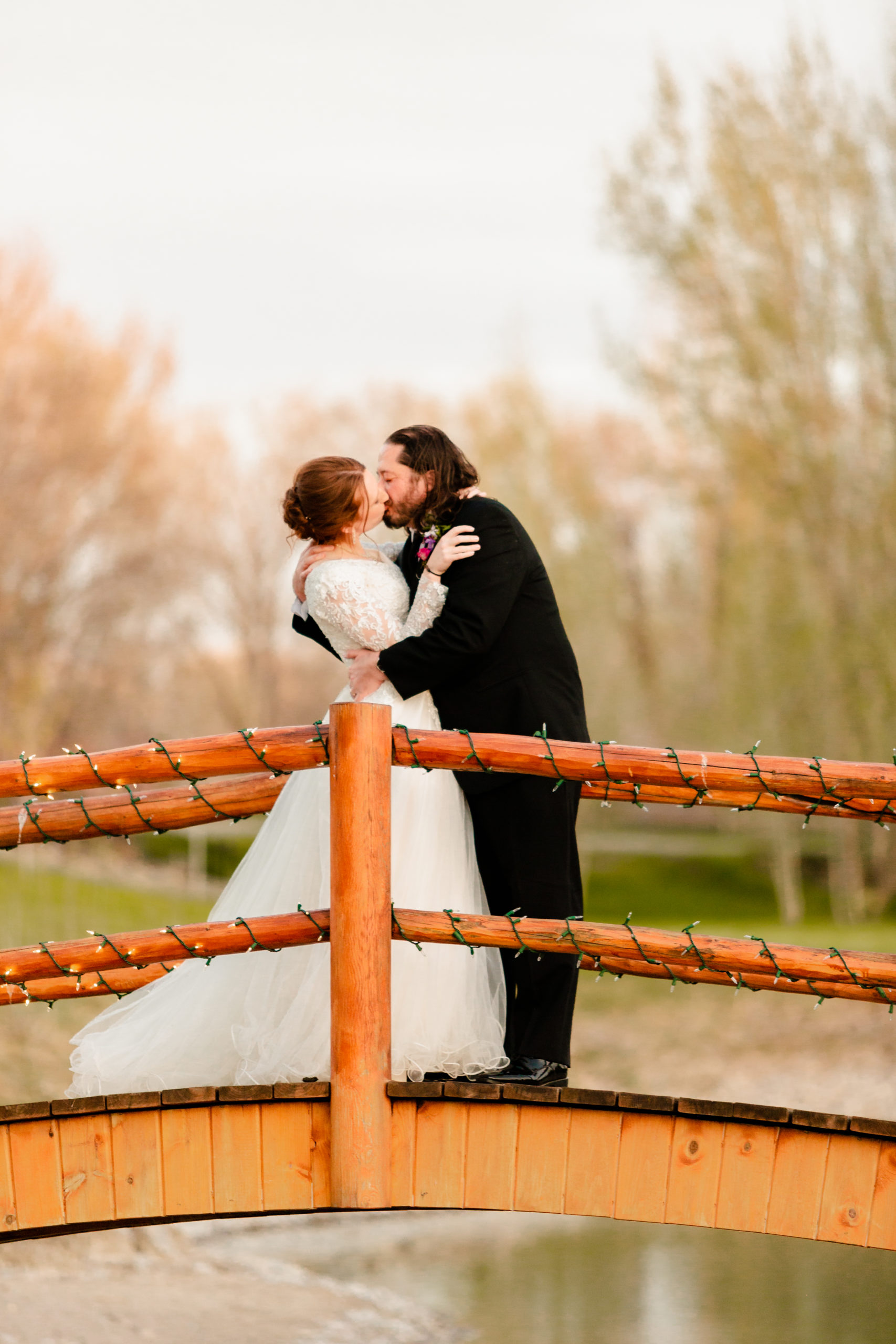 newly married couple embracing and kissing on bridge