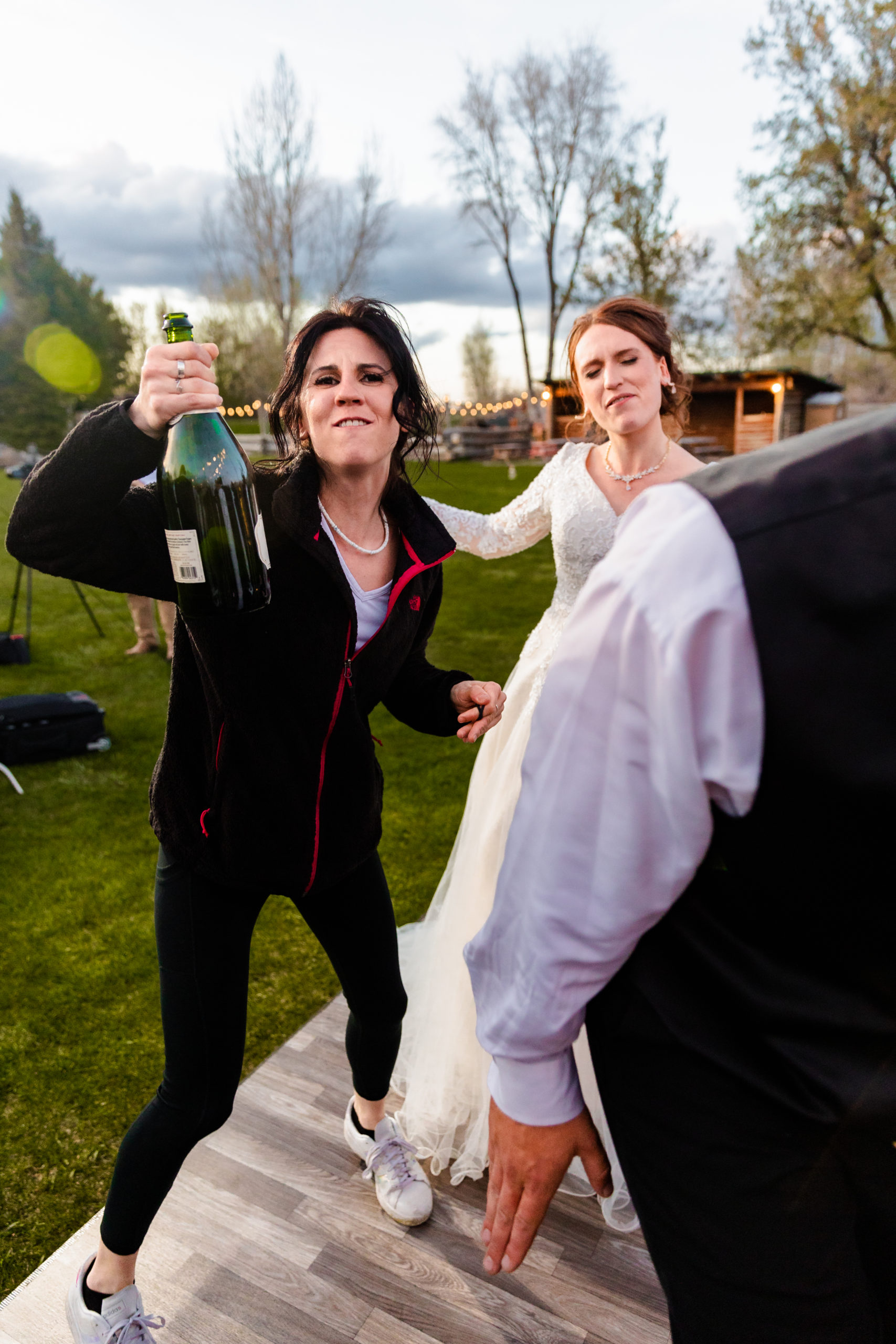 bride and wedding guest holding bottle dancing