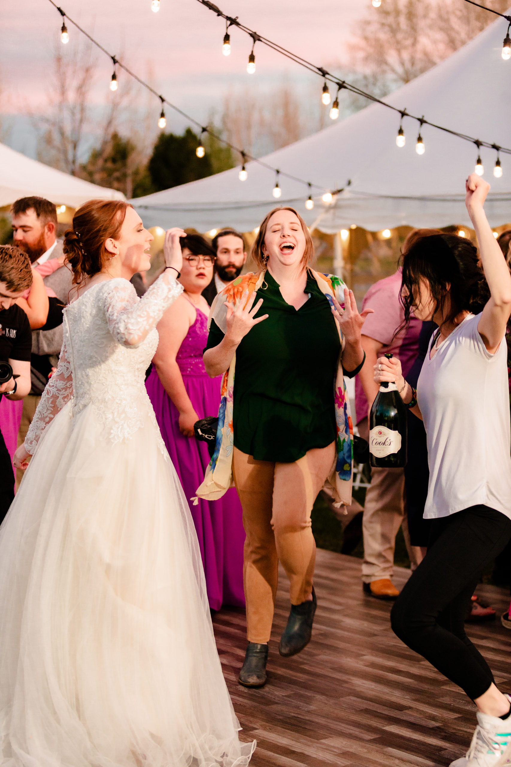wedding photographer jumping with wedding guests during sunset reception