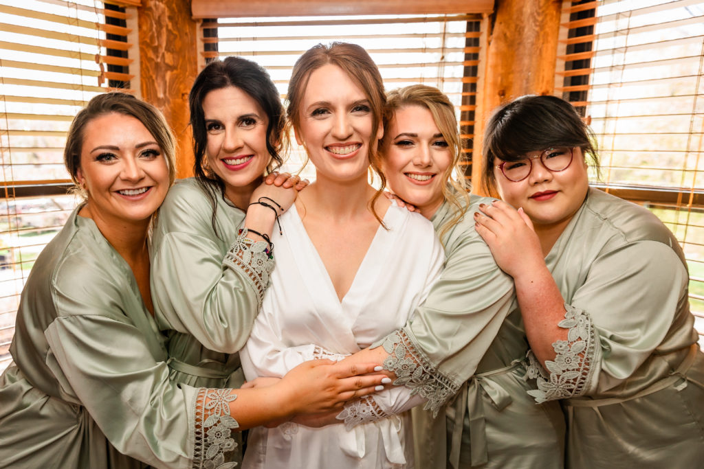 bride hugging bridesmaids in matching robes