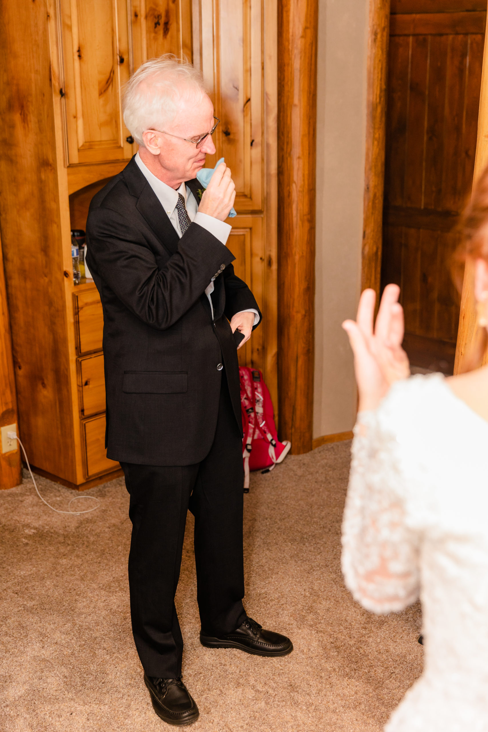 father of the bride wiping away tears as he sees his daughter as a bride