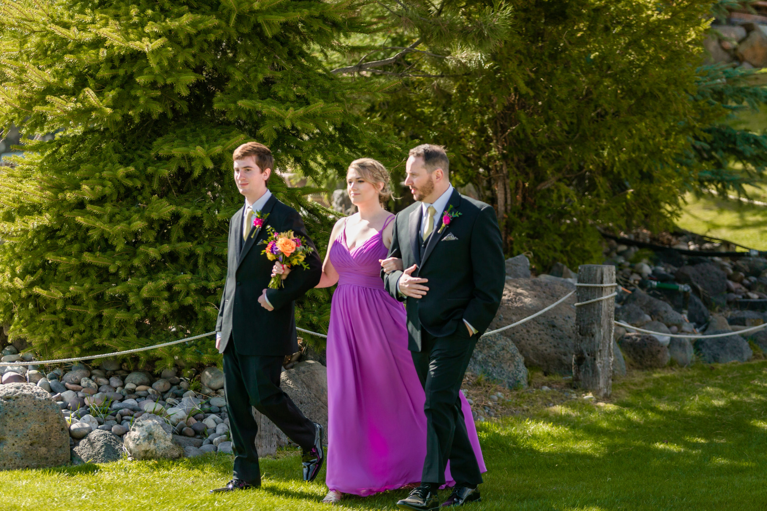 bridesmaid in purple walks with two groomsmen