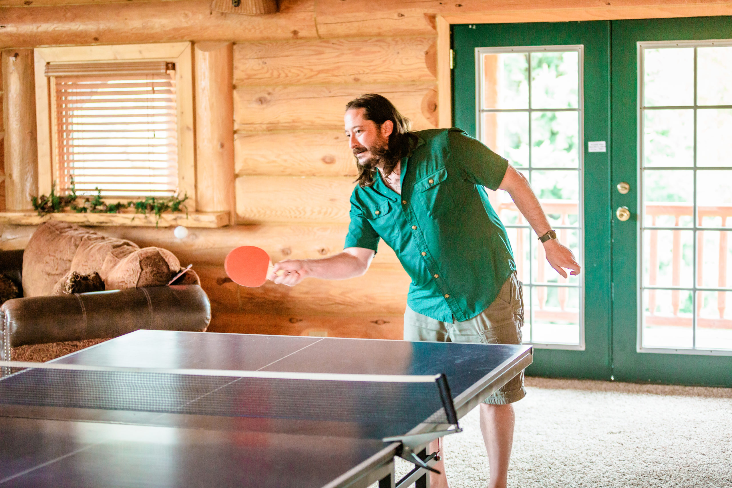groom playing ping pong at Labelle lake before wedding in green shirt and shorts