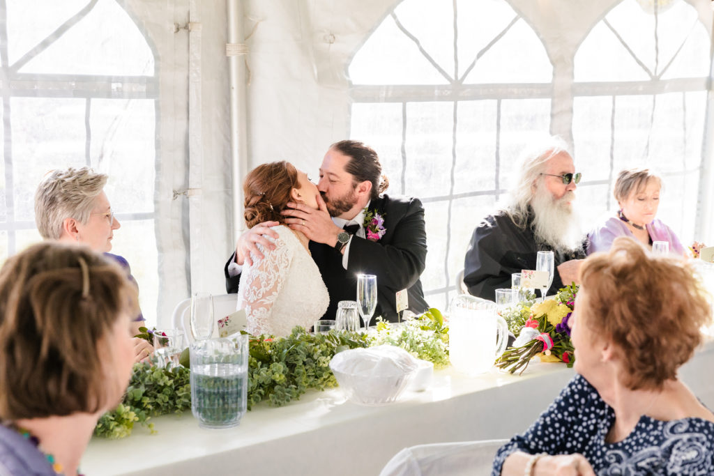 couple kissing after family toasts at colorful labelle lake reception