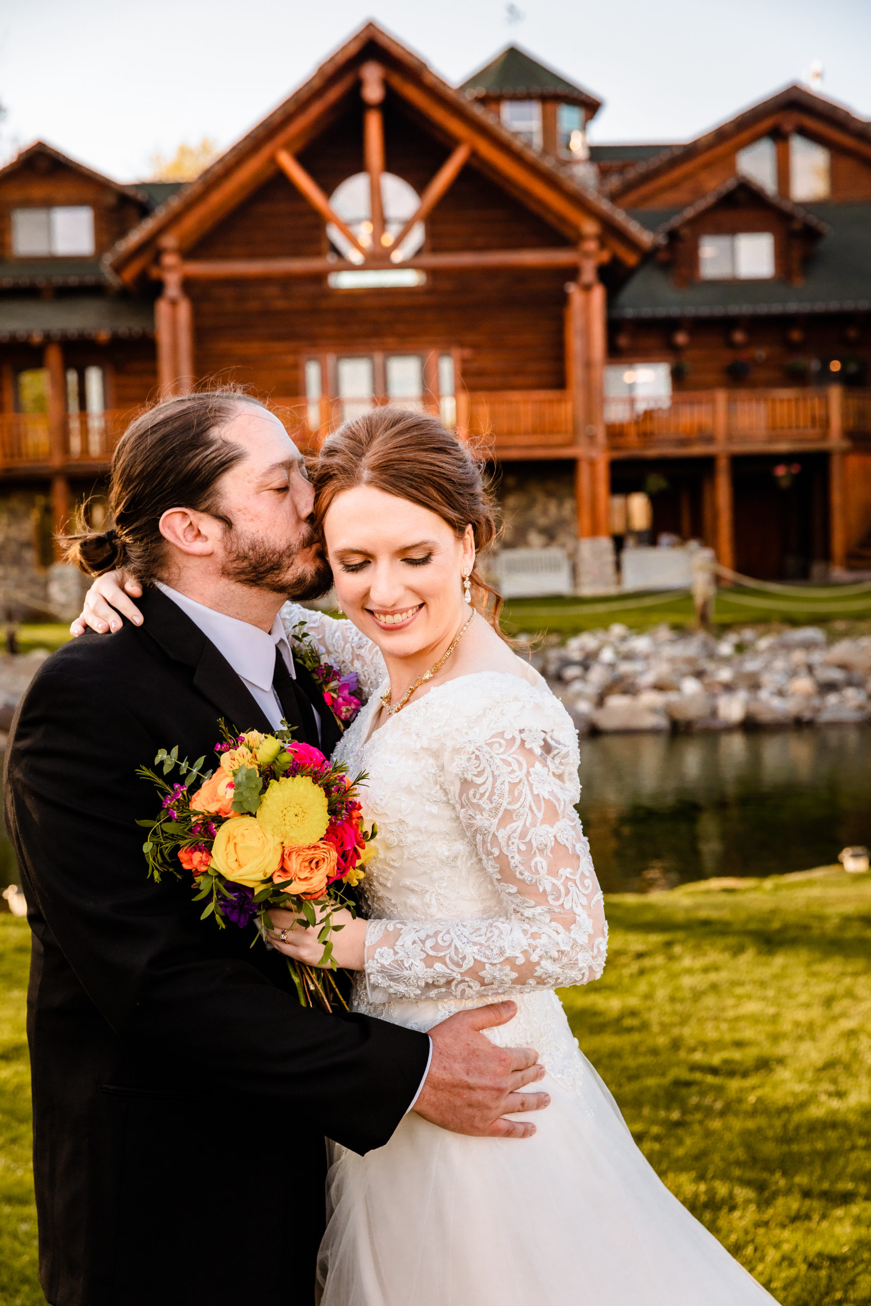 groom holding bride and kissing her forehead before Colorful LaBelle Lake Reception