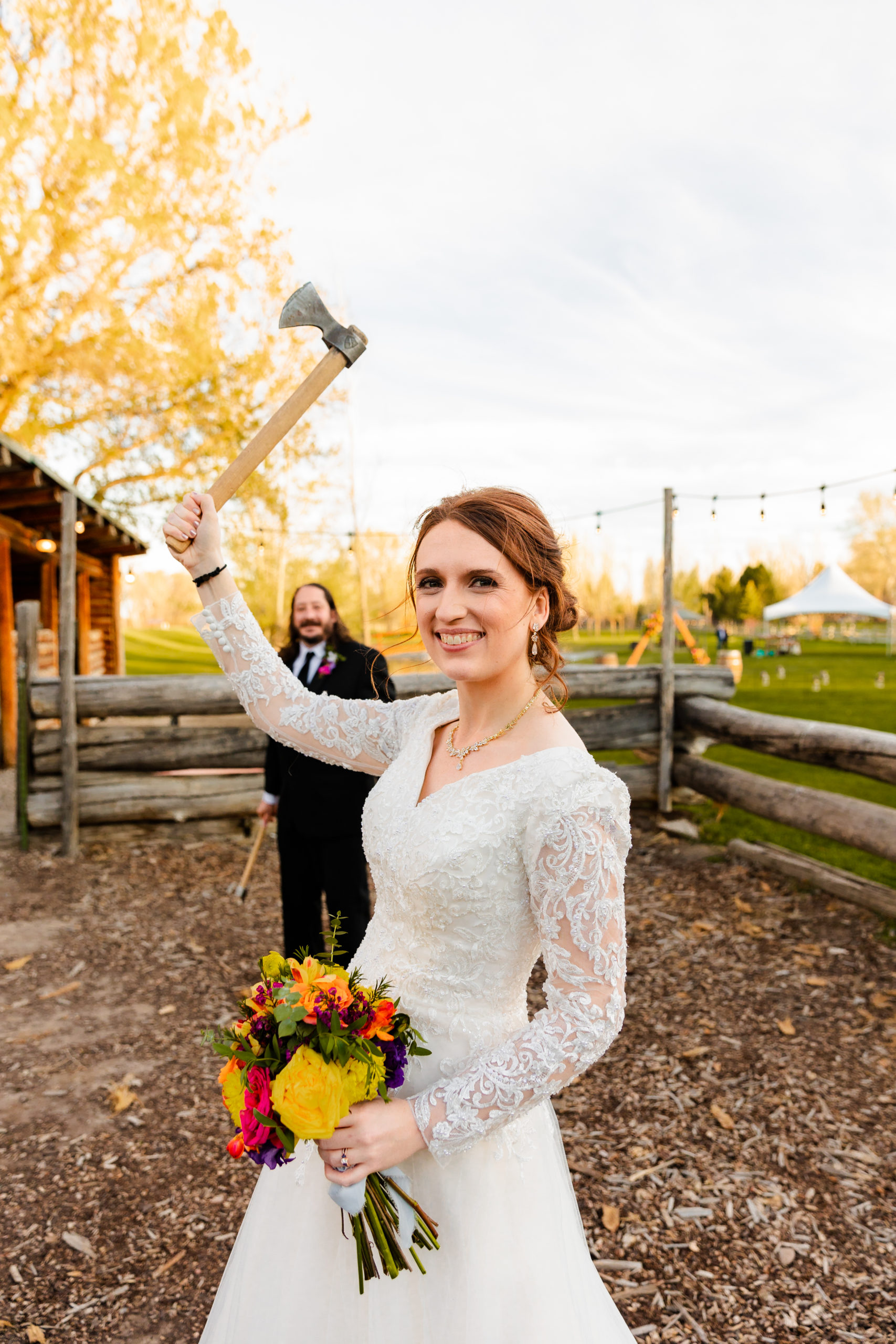 bride holding axe during axe throwing at wedding reception